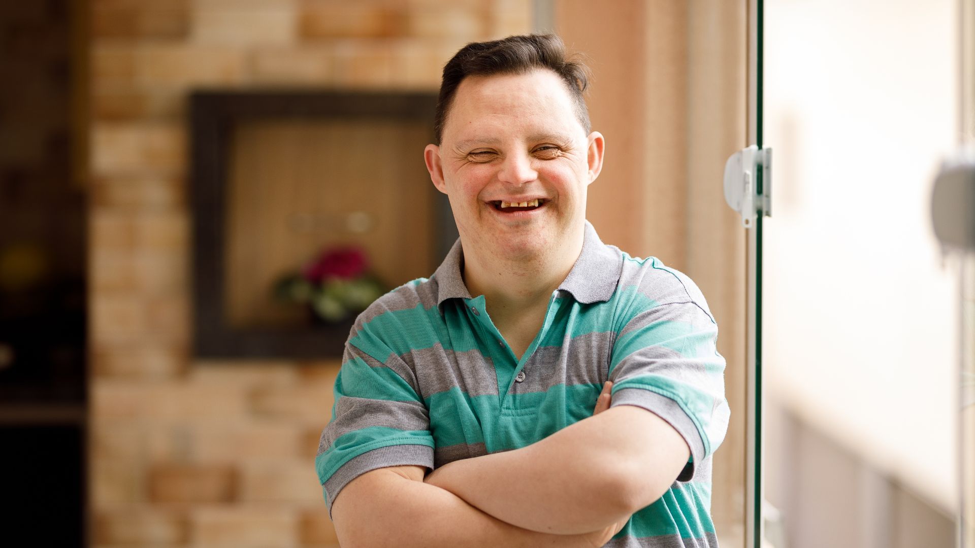 erson smiling with arms crossed while standing indoors