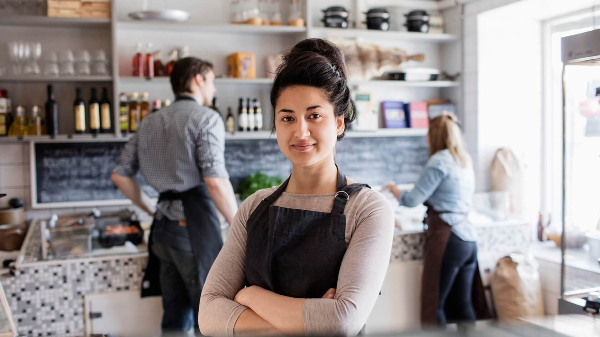 A retail worker stands in a store with her colleagues in the background