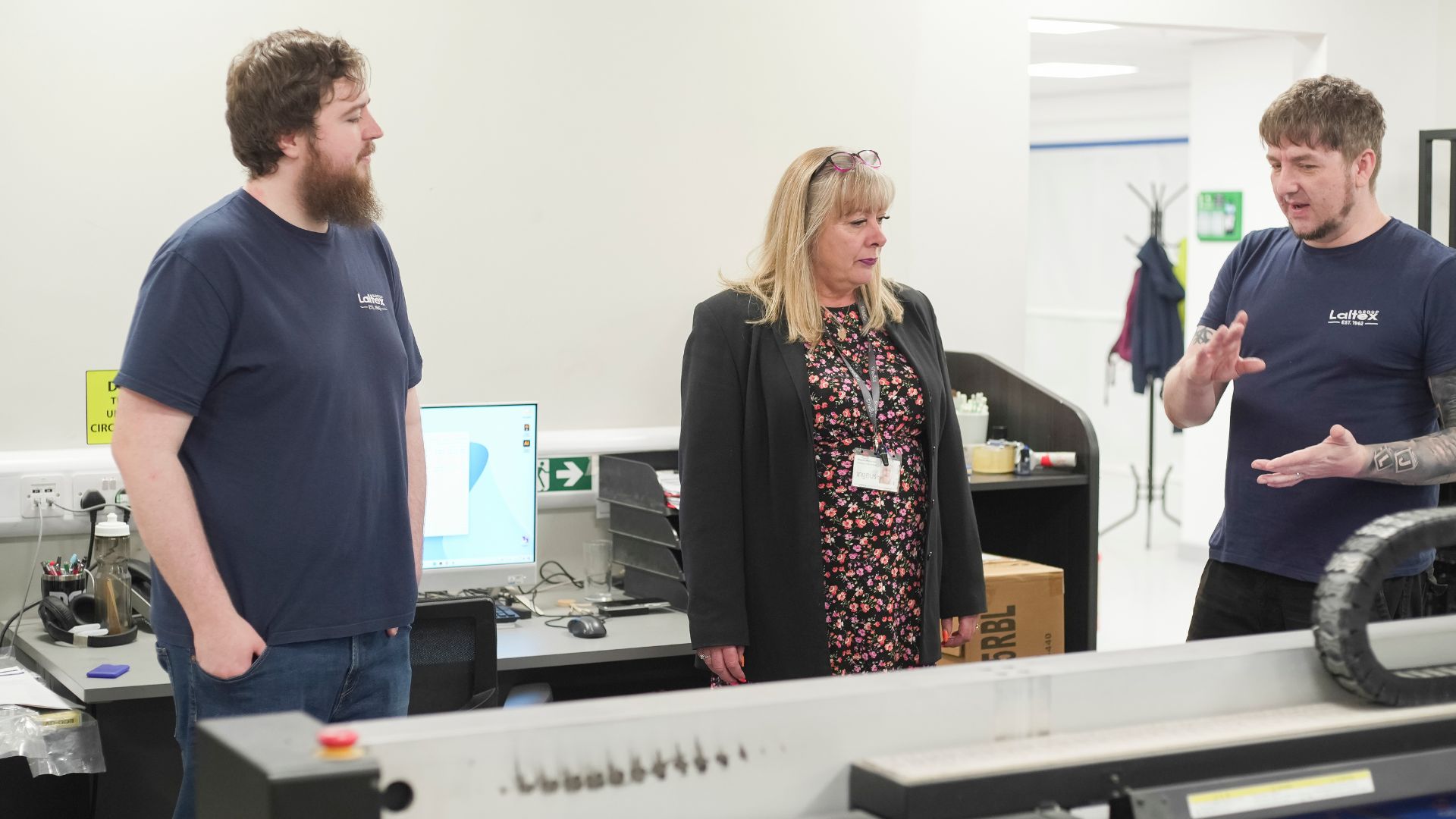 Fraser in a workshop setting with two other people near machinery, illustrating collaboration and career progress through Ingeus UK.