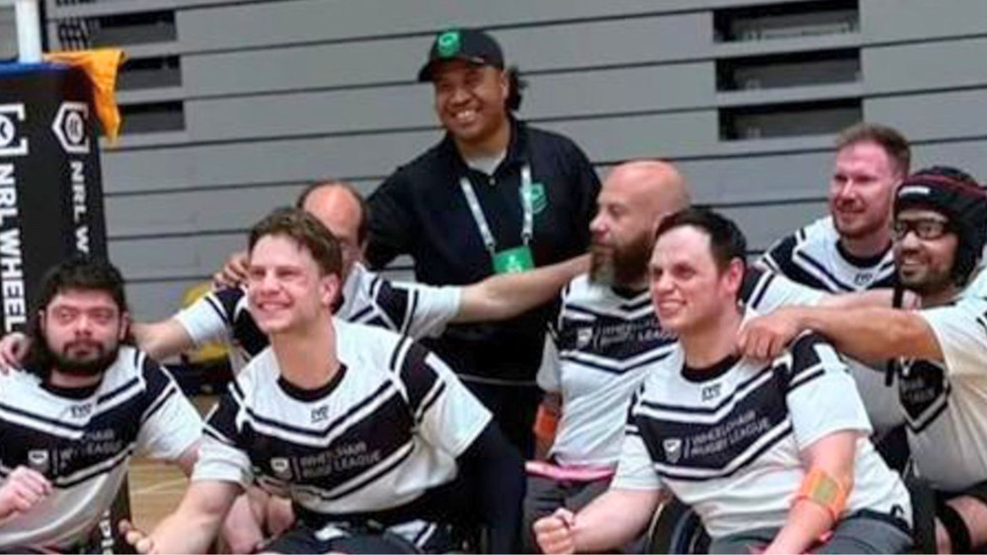 Members of the Victoria Wheelchair Rugby League team pose together in team uniforms at an indoor sports venue ahead of the NRL Wheelchair Championships.