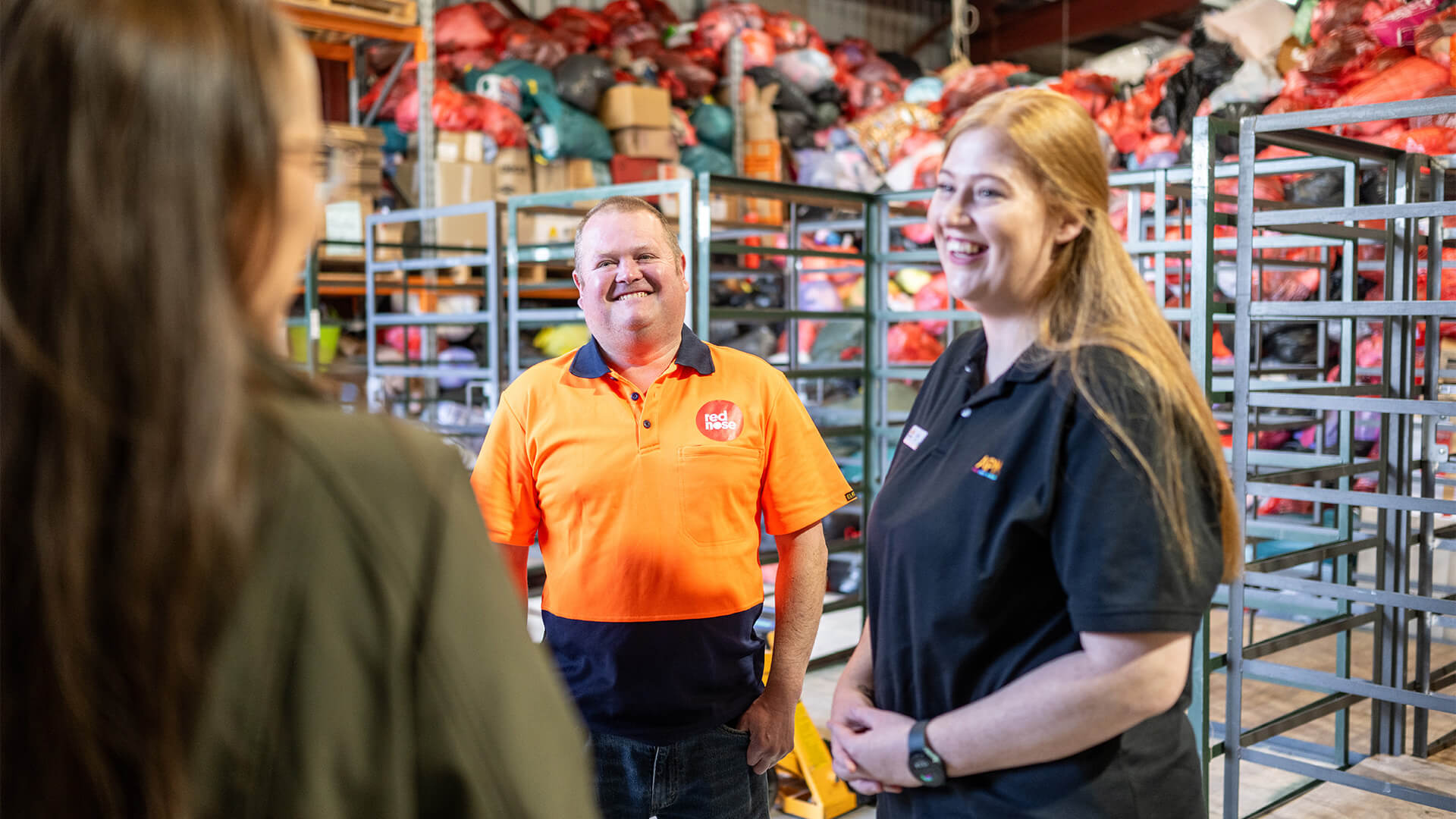 Participant in orange top talks to APM EC and employer in workplace