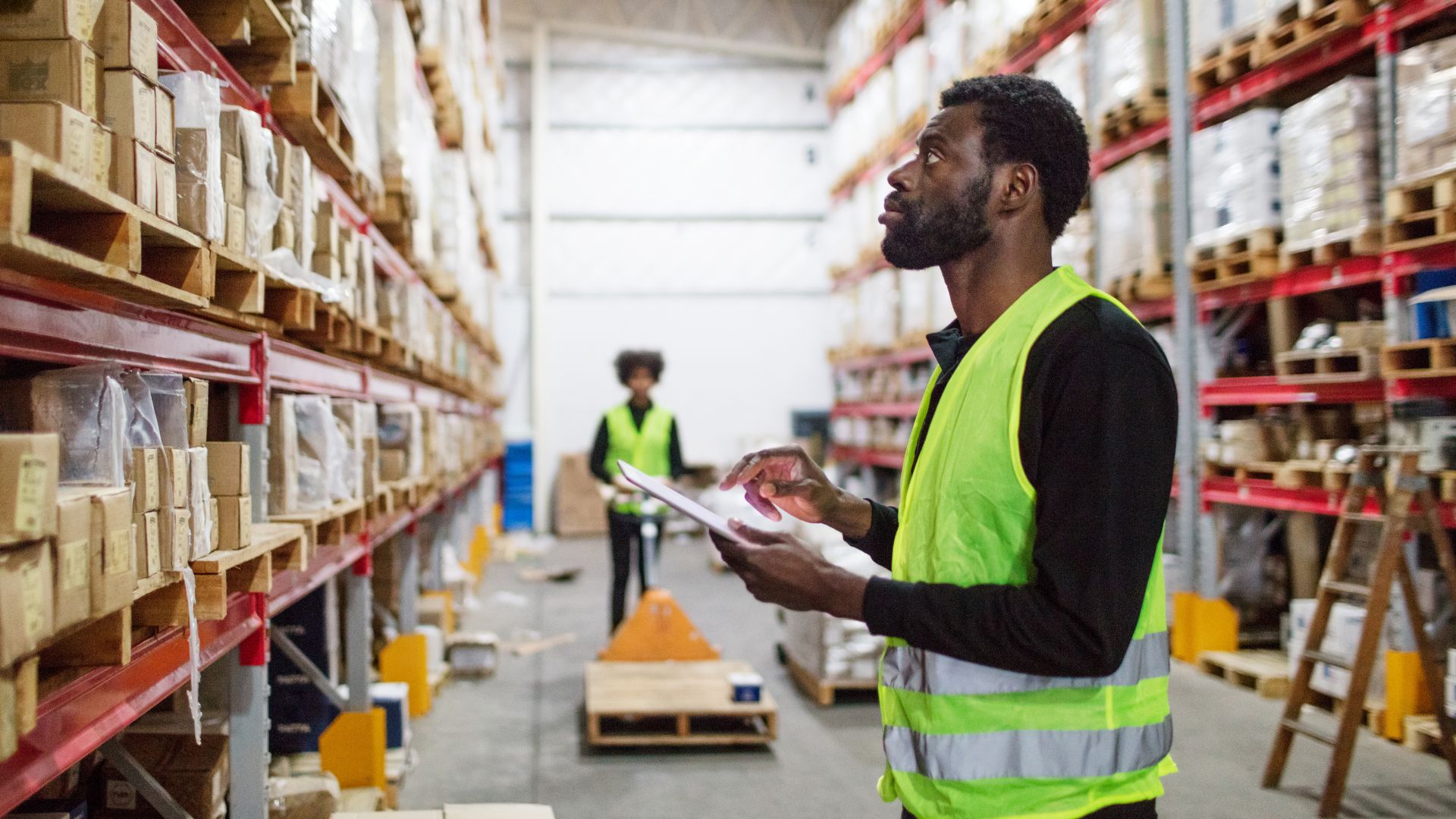 A man with a clipboard checking stock in a warehouse