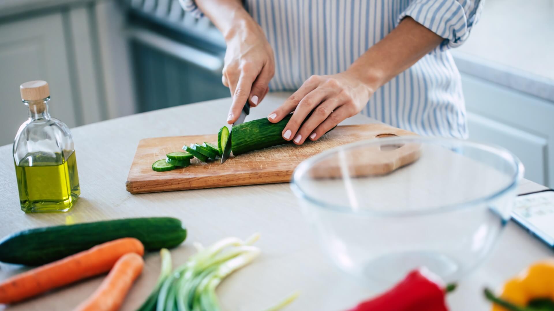 A close up of a woman chopping vegetables in her home
