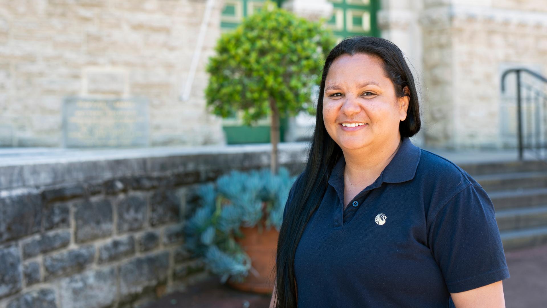 Narelle in a navy polo shirt smiling outside