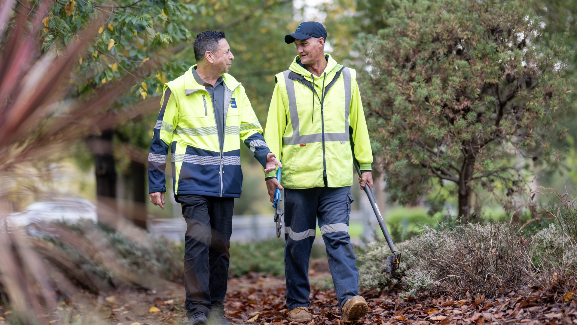 Paul walking and talking with a workplace supervisor while working in park maintenance, highlighting employment opportunities and ongoing workplace support through Inclusive Employment Australia and APM Employment Services.