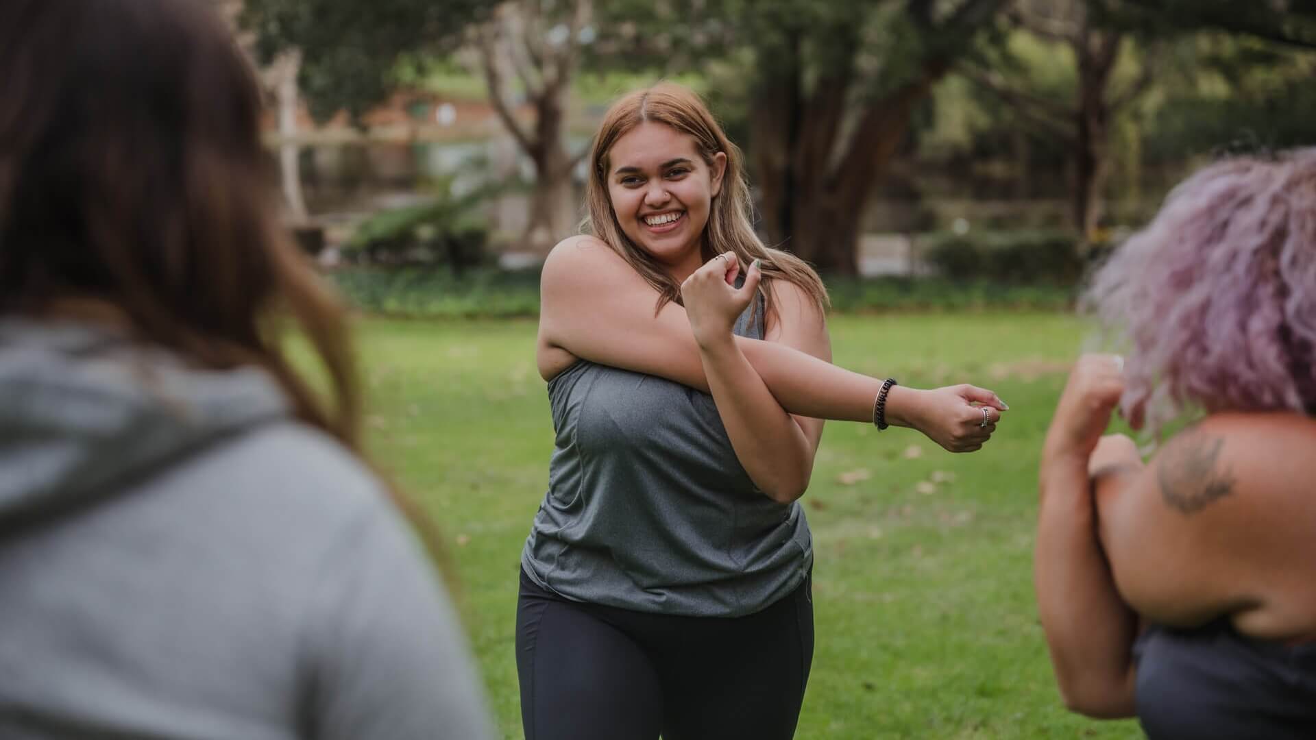 A woman smiling while stretching in a fitness class