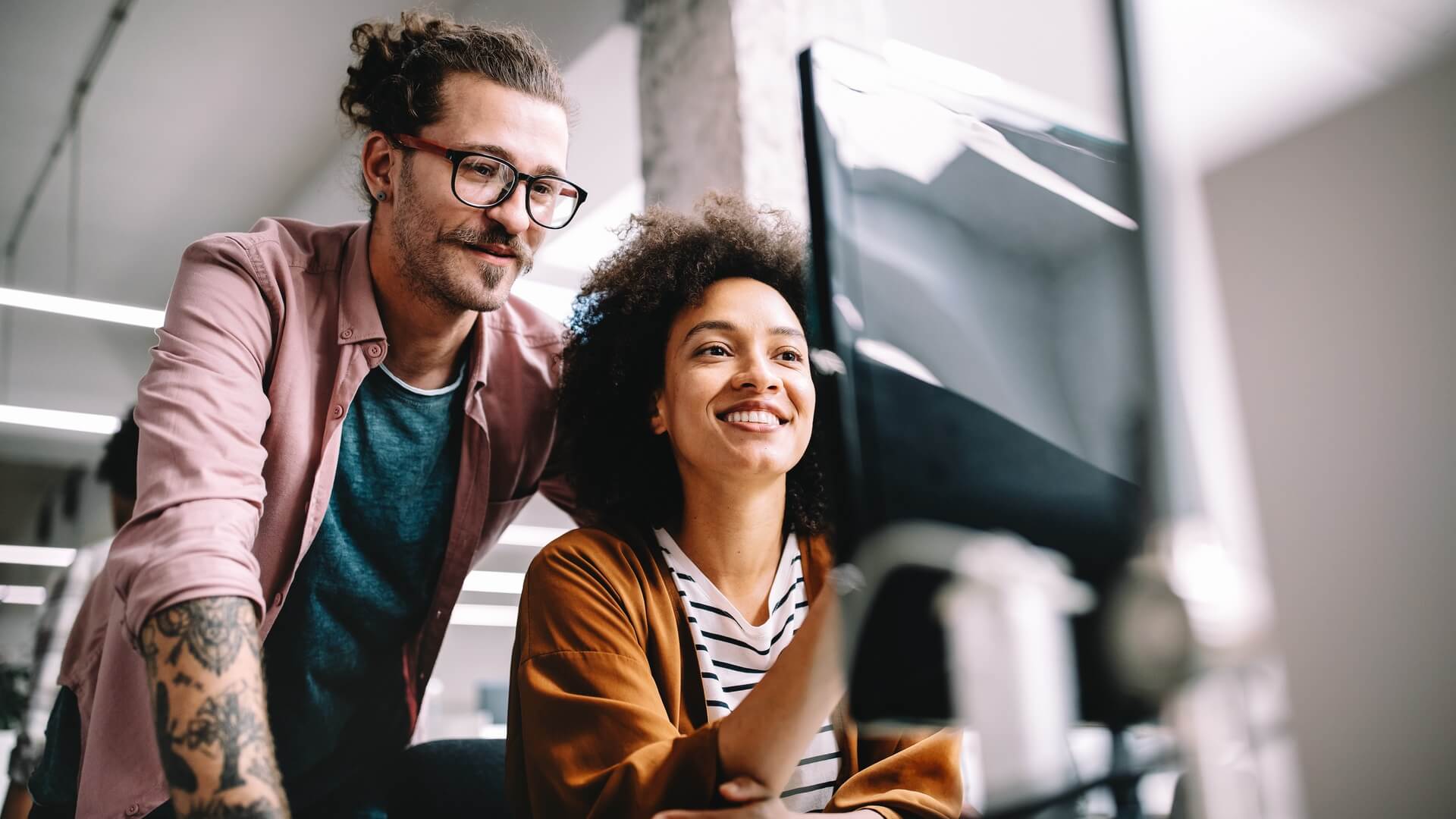 Two smiling co-workers discussing a project