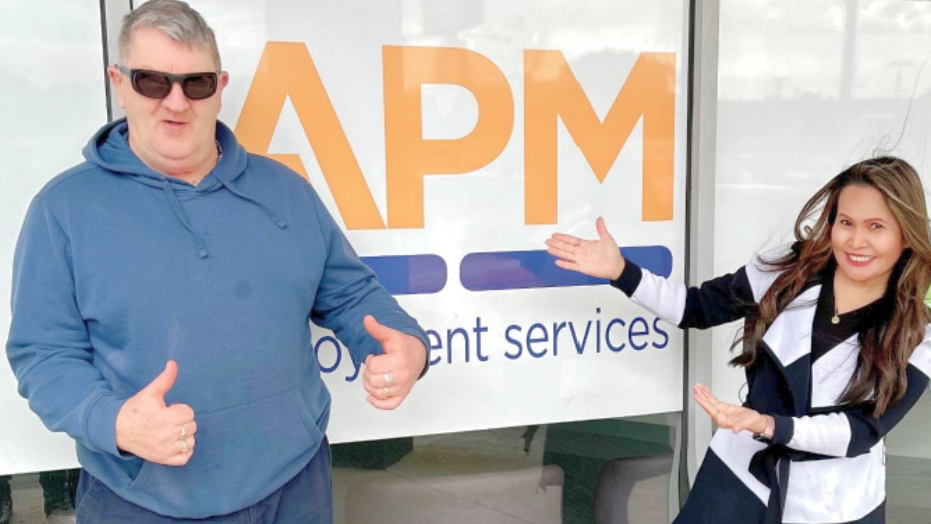Michael and Cecile outside next to an APM sign