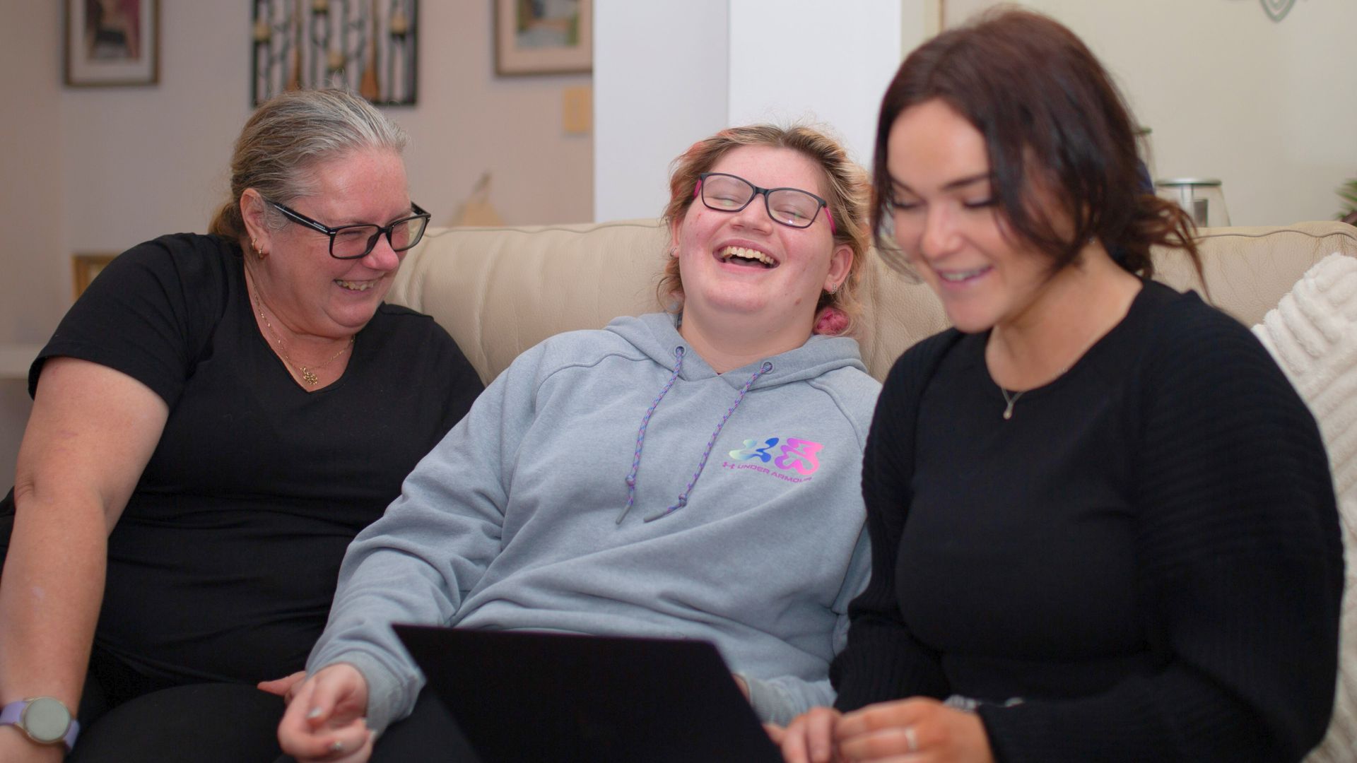 Amy sitting on a couch with her mum Heather and Occupational Therapist Scarlette, discussing goals and supports at home. Everyday Independence story about collaborative therapy and family involvement.