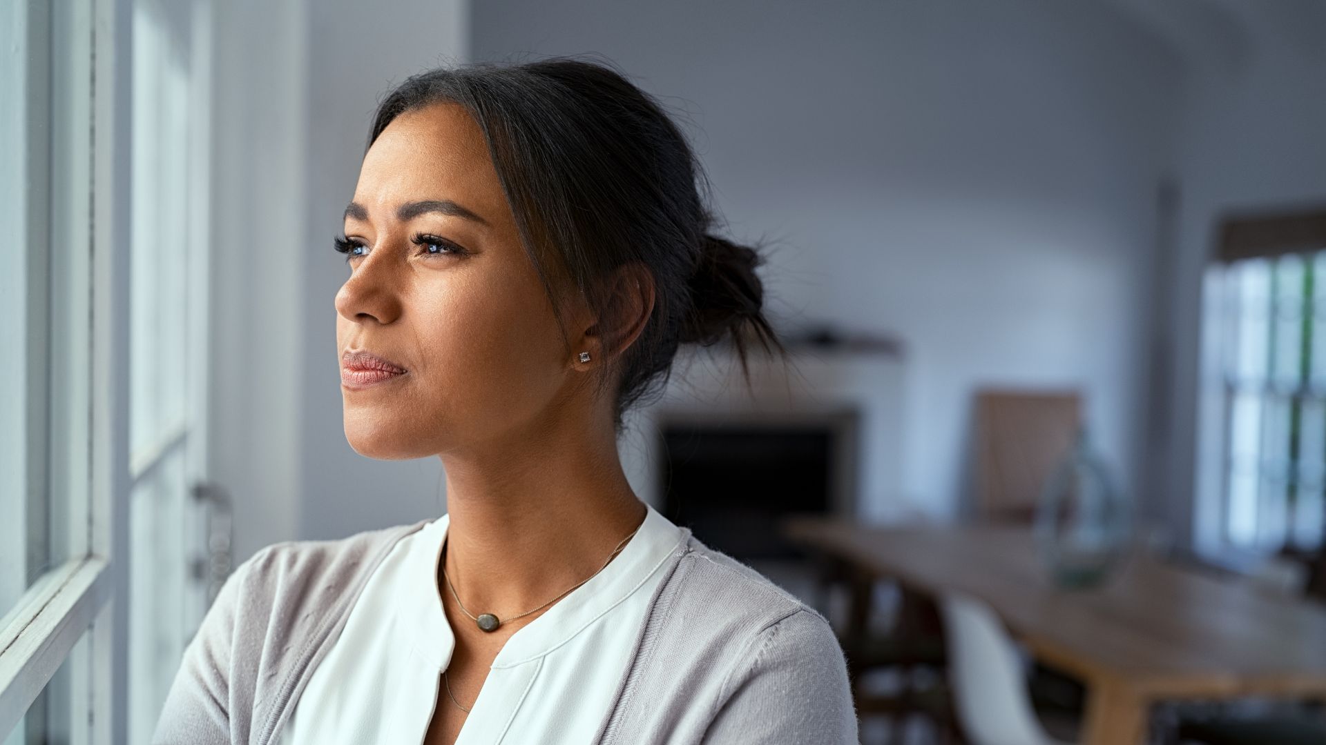 Woman look out a window to show depression