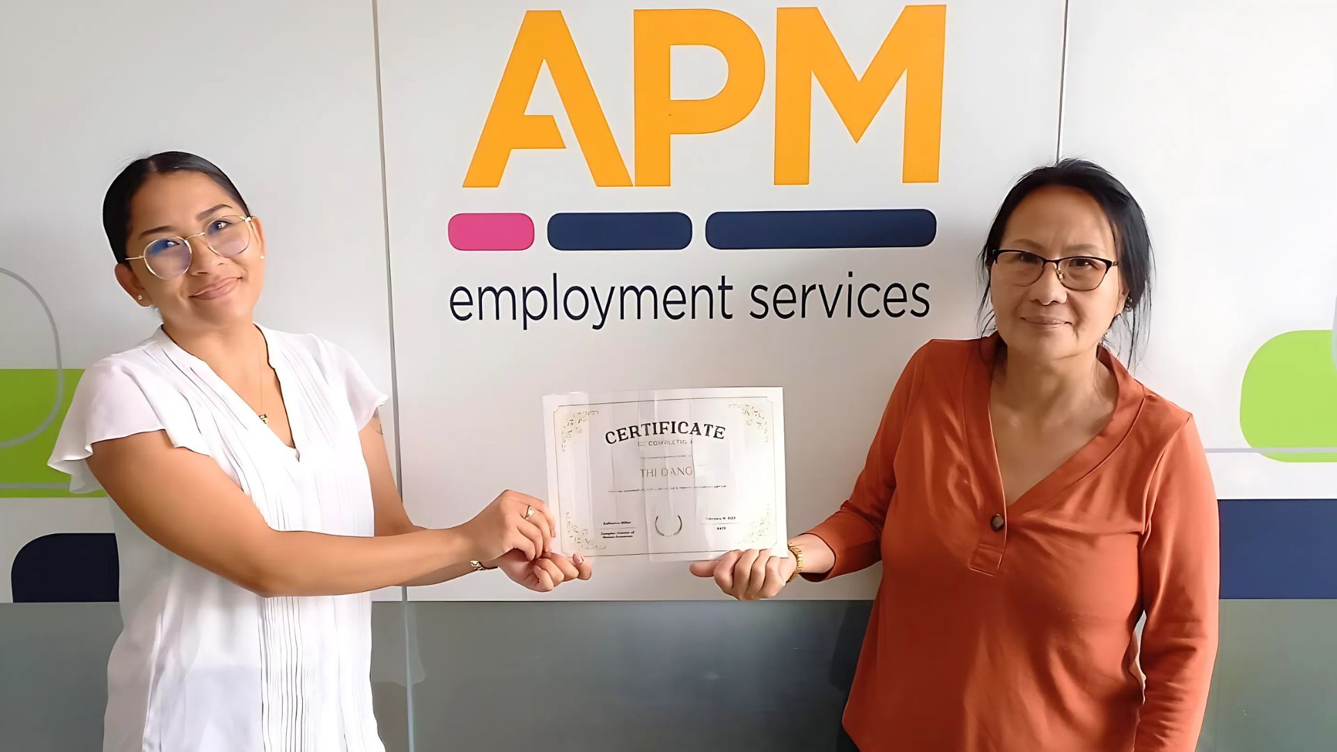 Thi and Almaree smile outside an APM branch