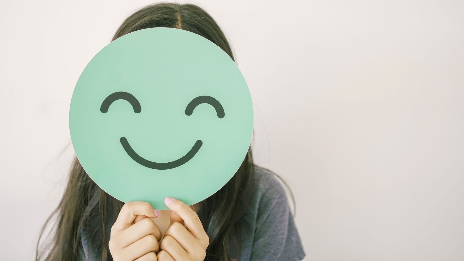 A woman with a smiley face in front of her face to show anxiety