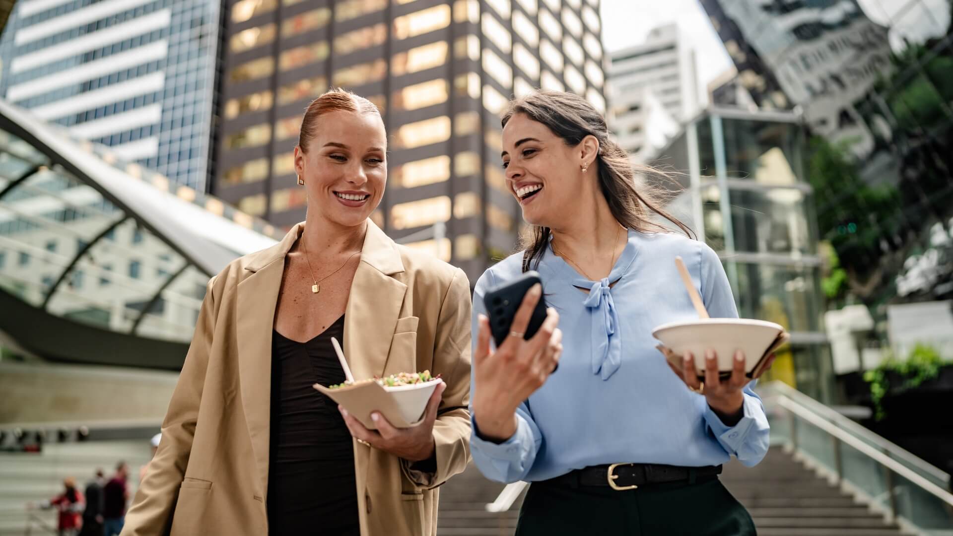 Two women walking back to their office with takeaway salads