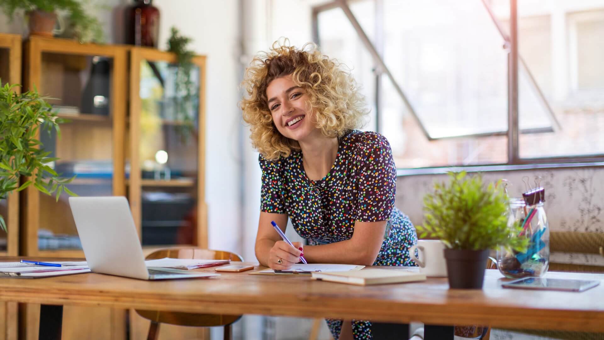 A woman leaning on her work desk and smiling