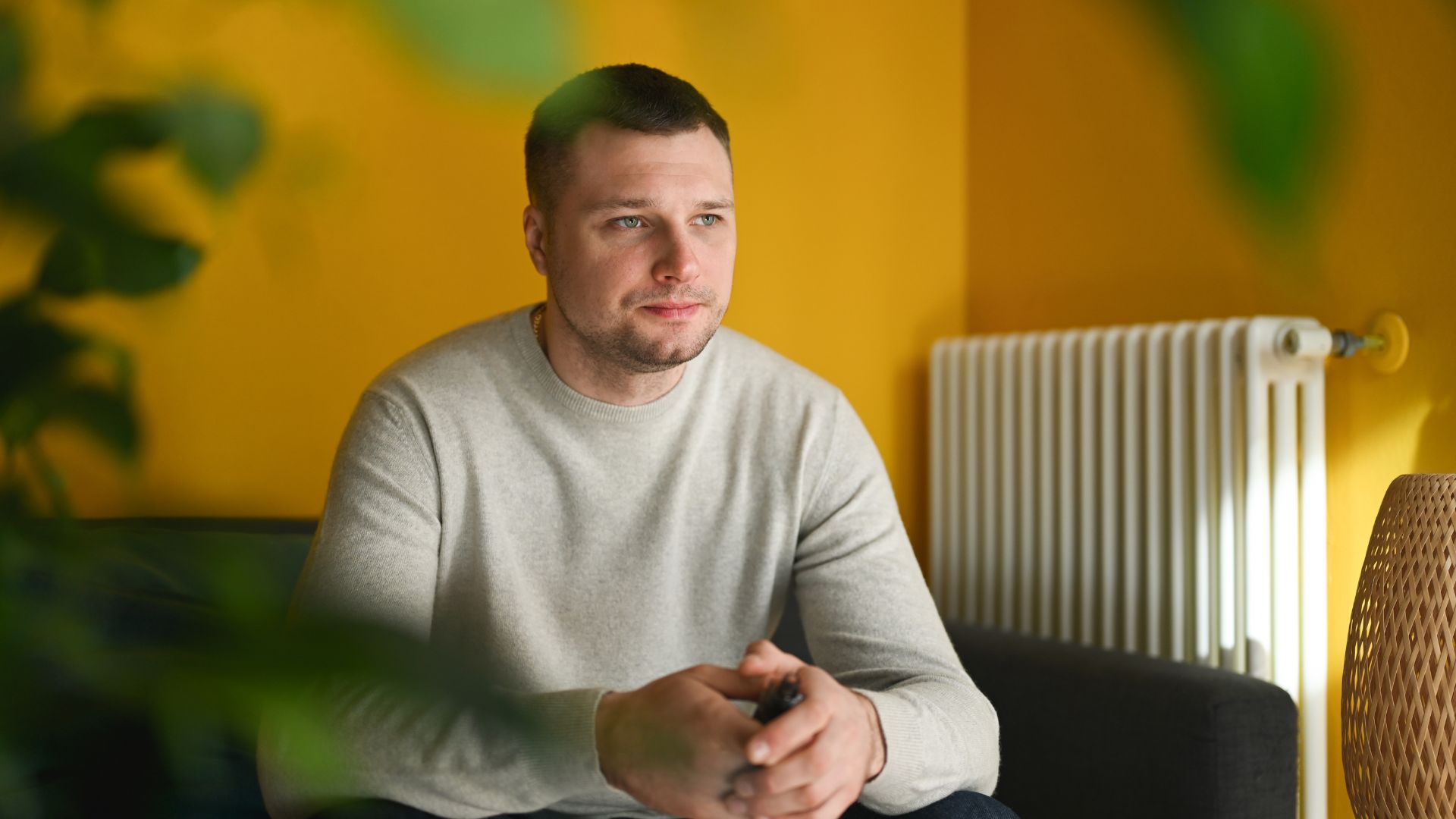 Person sitting on a couch in a yellow room, representing moments of quiet reflection while living with schizophrenia.