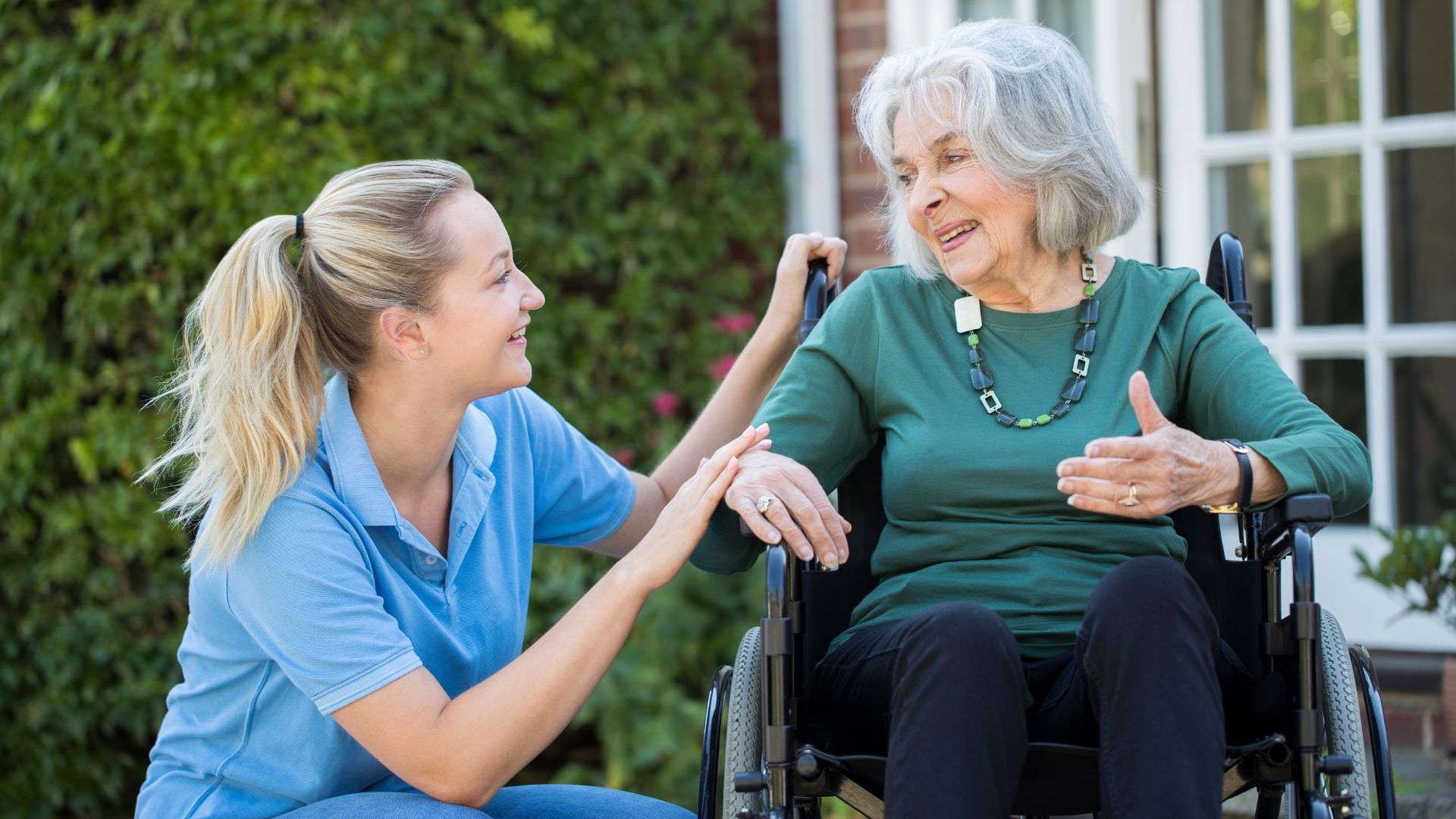 A carer smiles with an older woman in a wheelchair