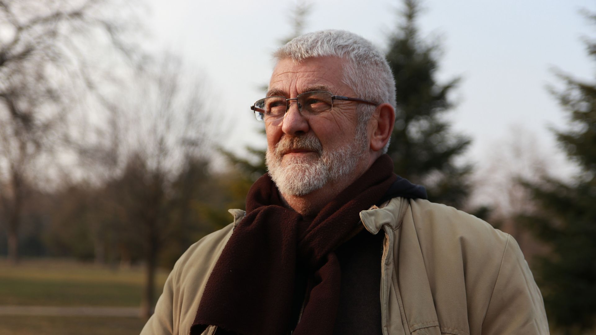 Person standing outdoors in a quiet park, representing moments of reflection that may occur when exploring early signs of schizophrenia.