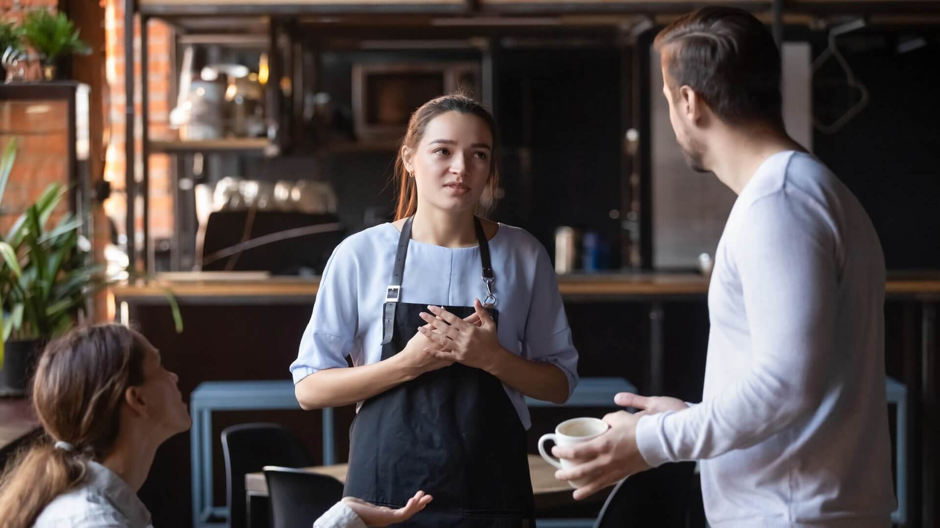 A waitress talking to two customers in a cafe