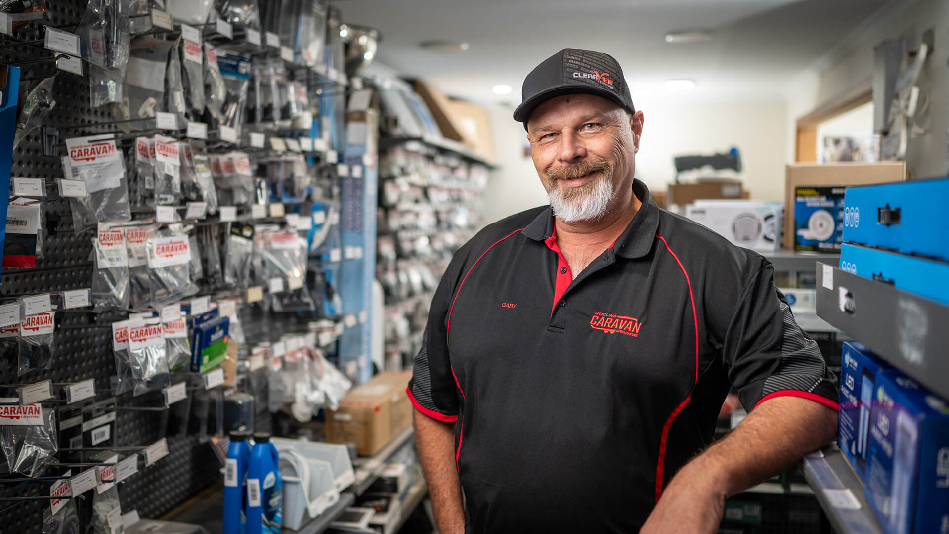 Worker Gary in an aisle of a shop smiling