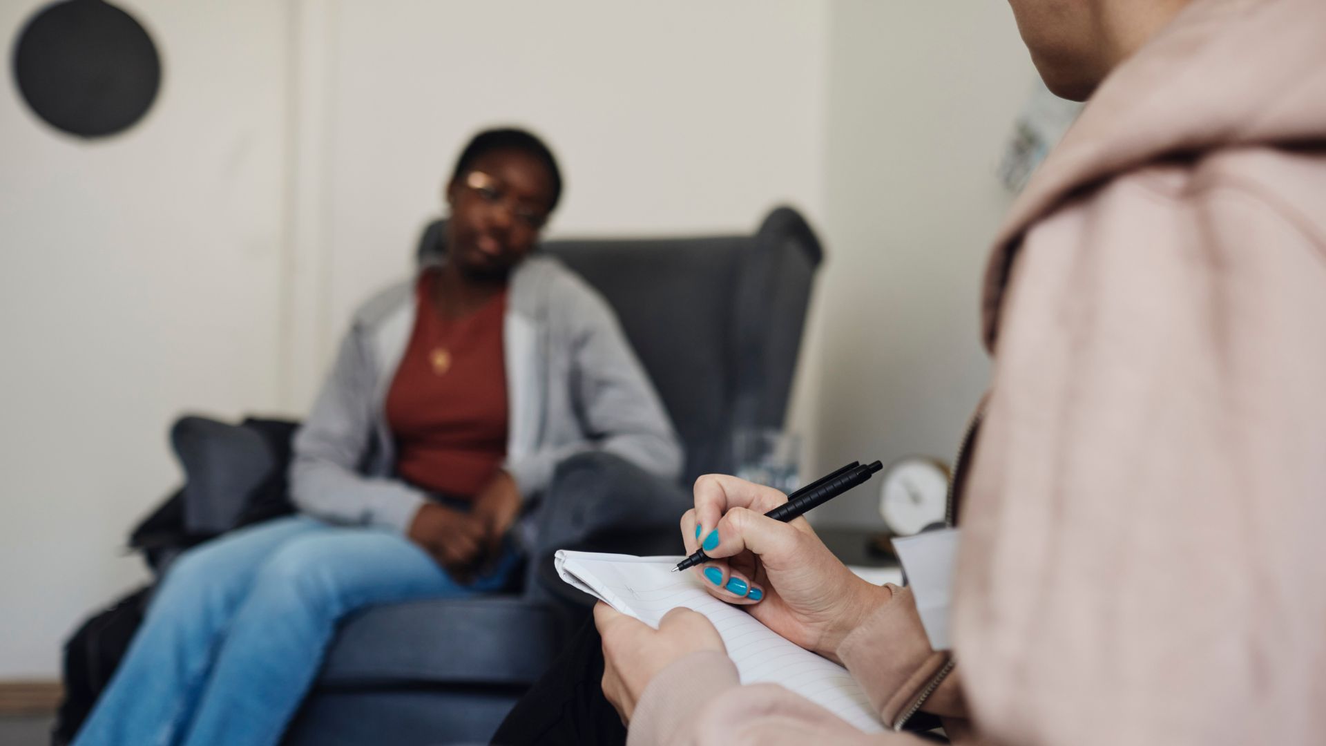 Mental health professional taking notes during a therapy session, supporting someone living with schizophrenia.
