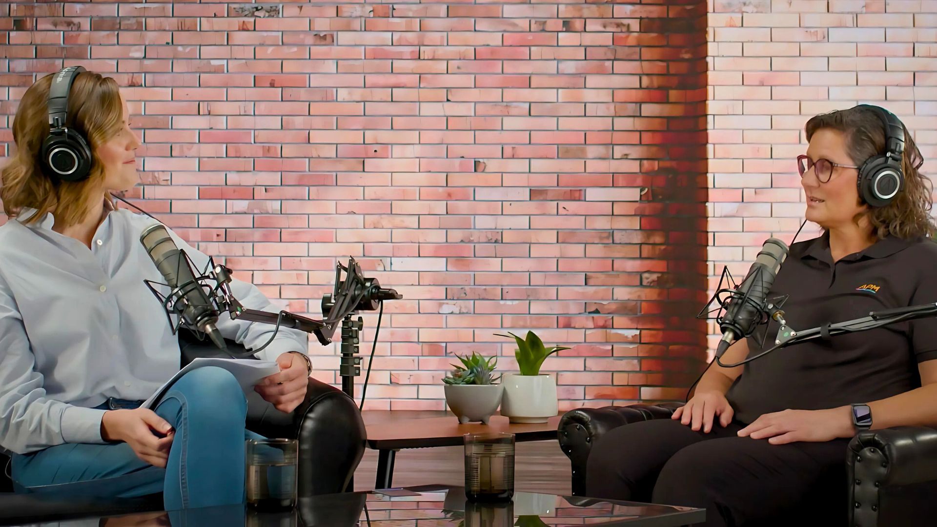 Ellie and Els from APM sit in chairs by microphones