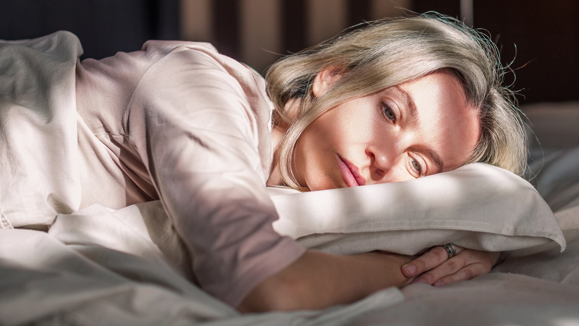 Despondent woman lying on bed at home