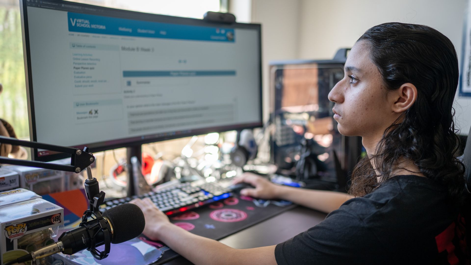 Conrad sitting at a desk with a large monitor and gaming equipment, using technology in a supportive home environment thanks to MyIntegra.