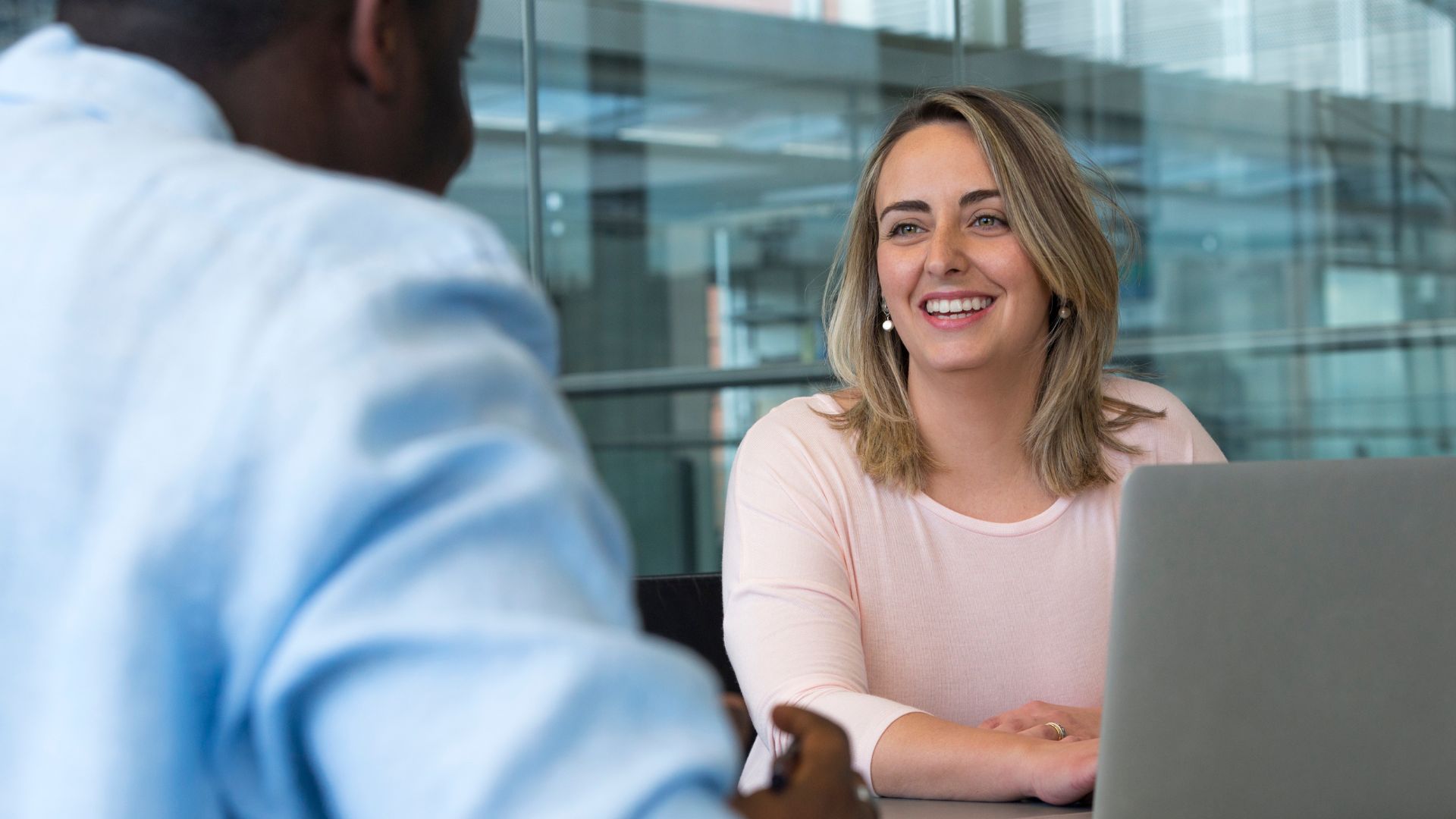 Woman smiles at an office desk with laptop