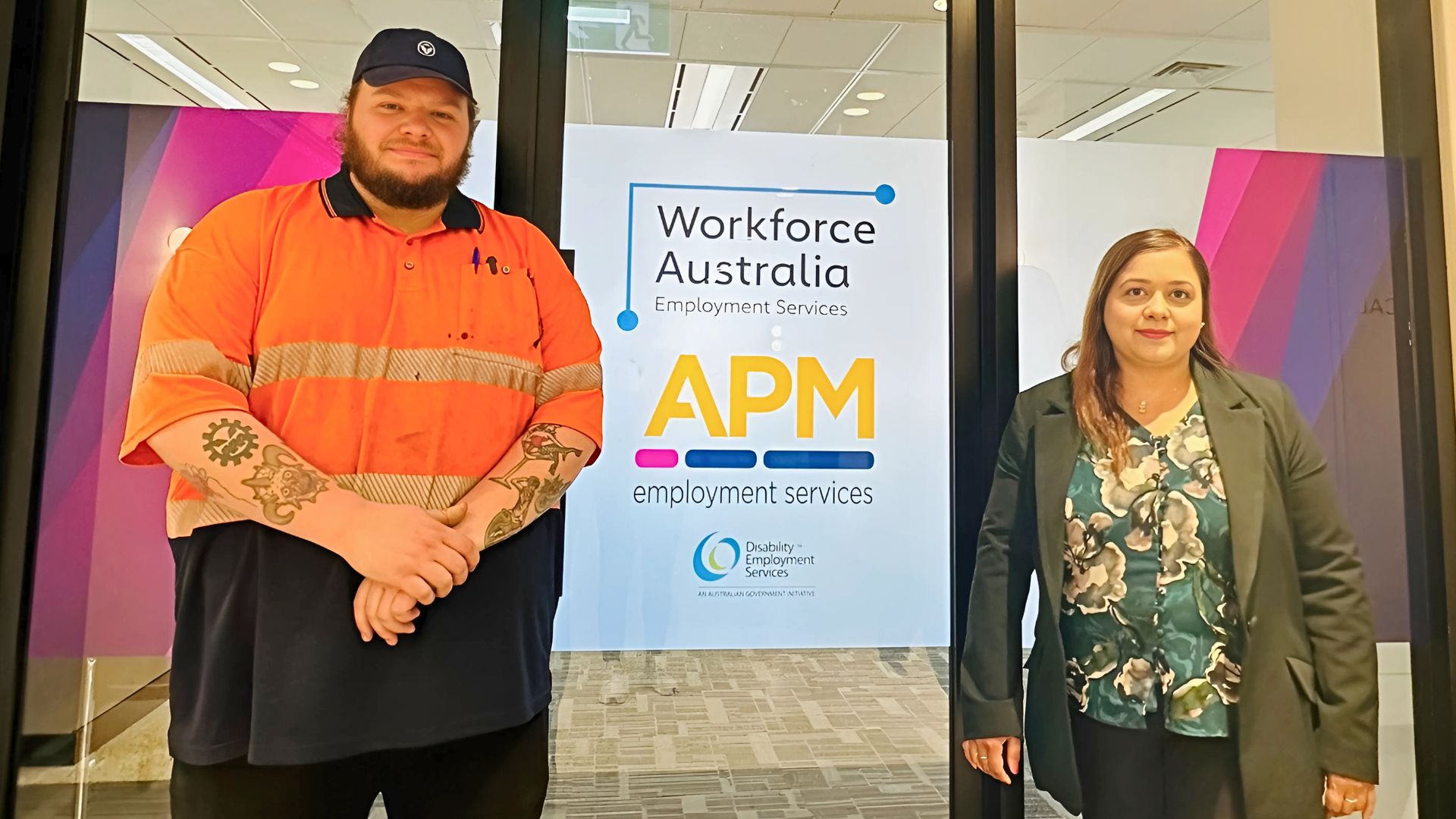 Harrison with Sarwat from APM Employment Services next to a sign for Workforce Australia