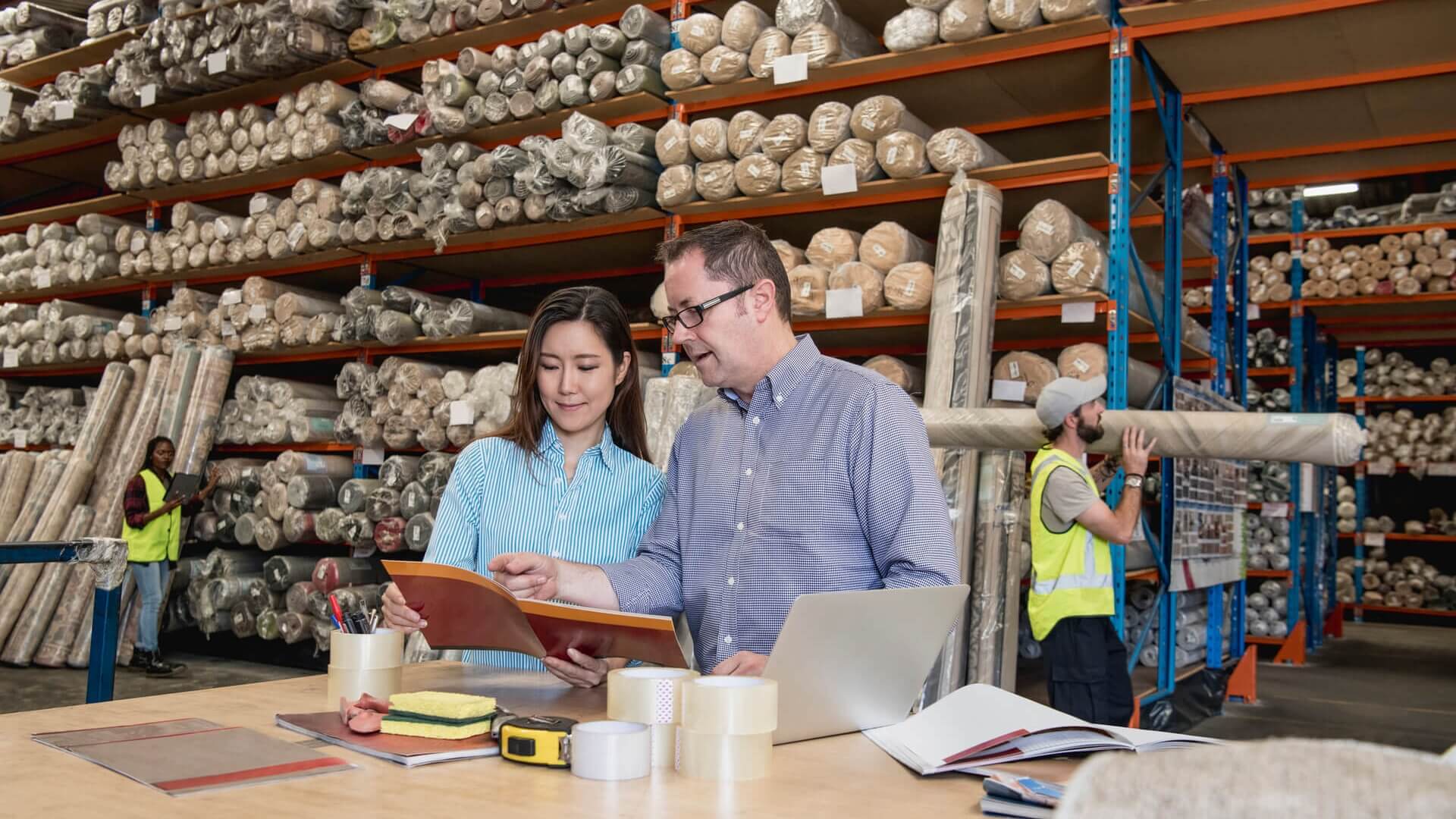 Two colleagues discussing a report in a warehouse