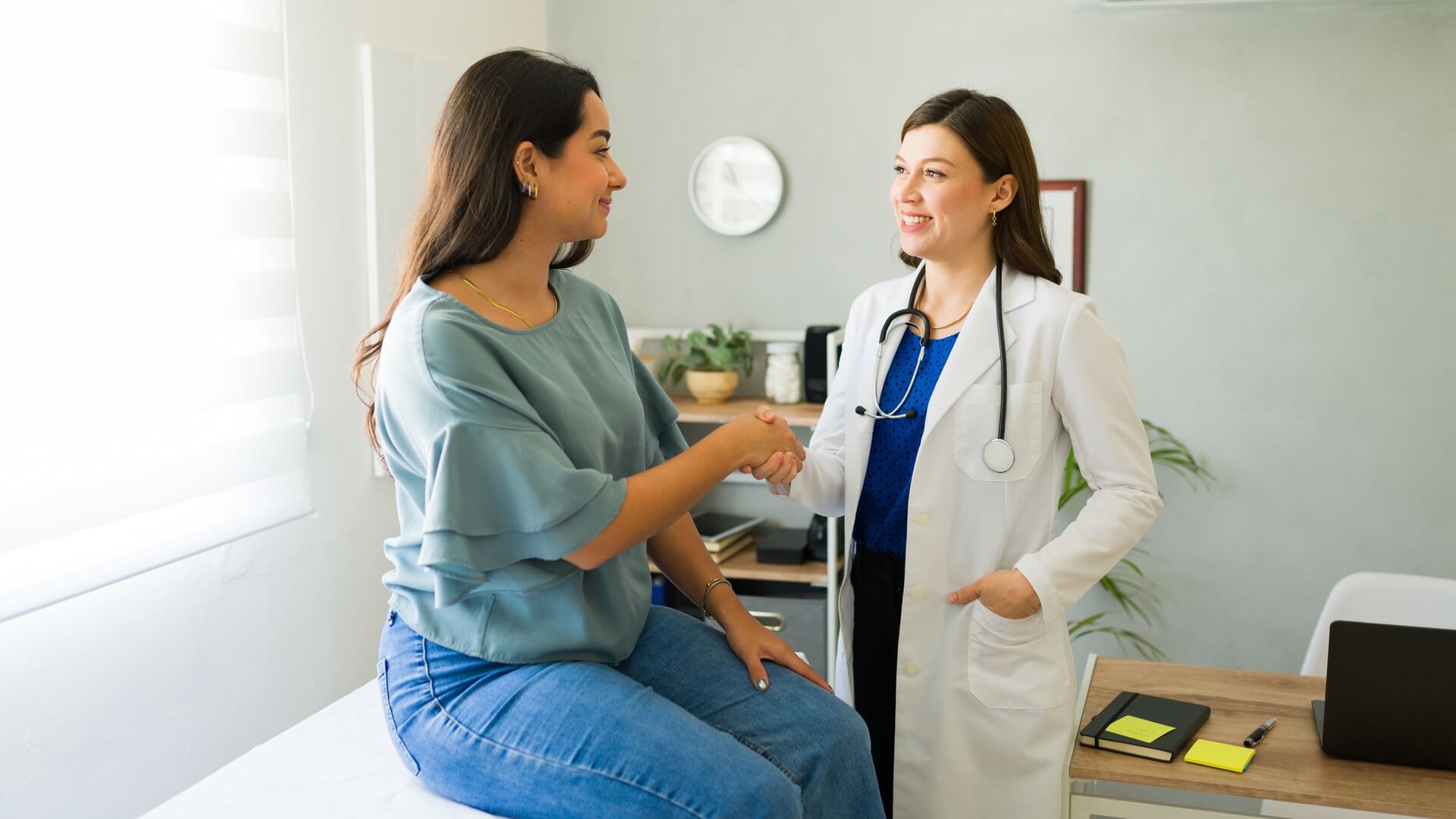 A woman greets her doctor from the exam table