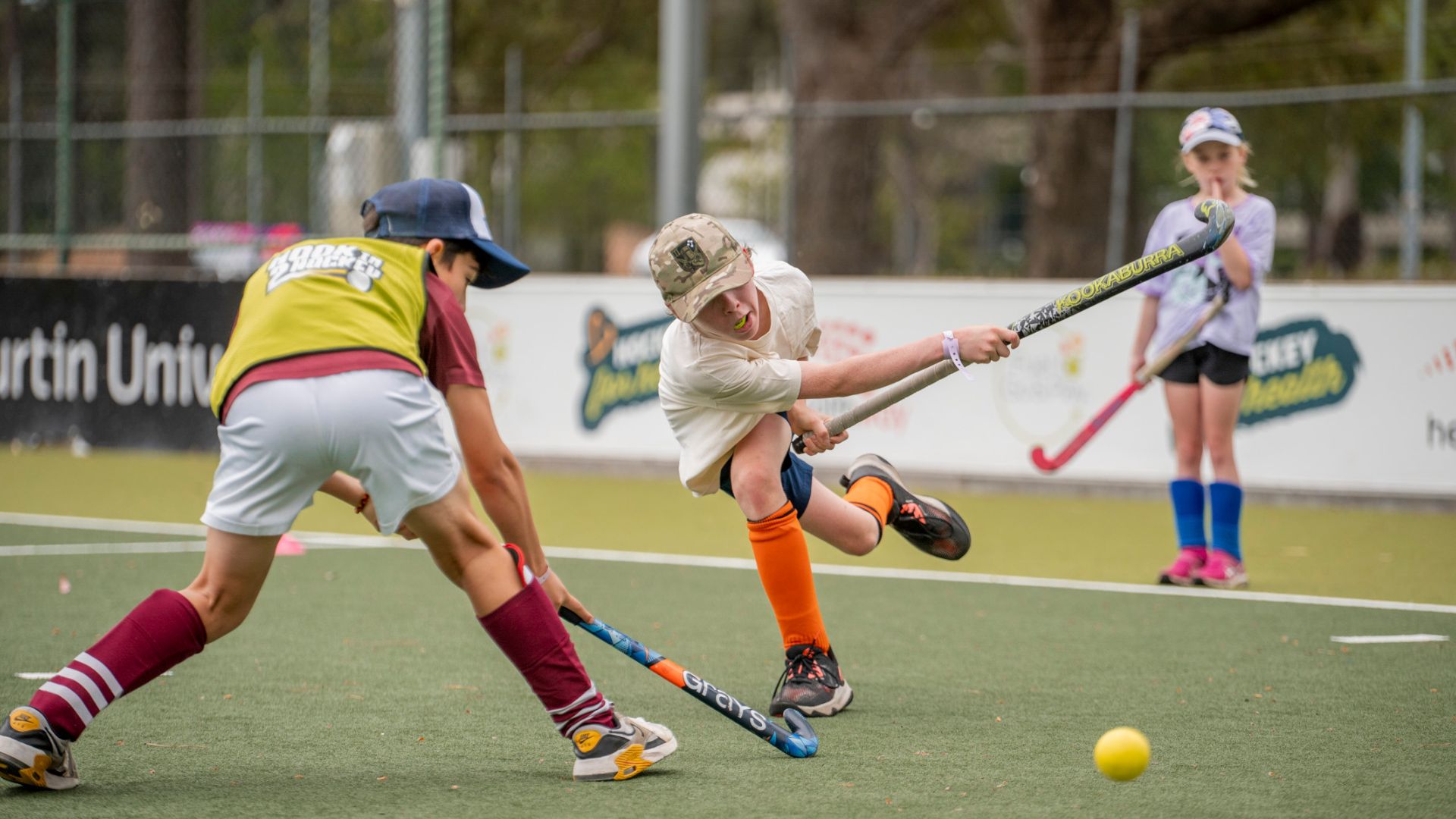 A young player takes a shot on the hockey pitch