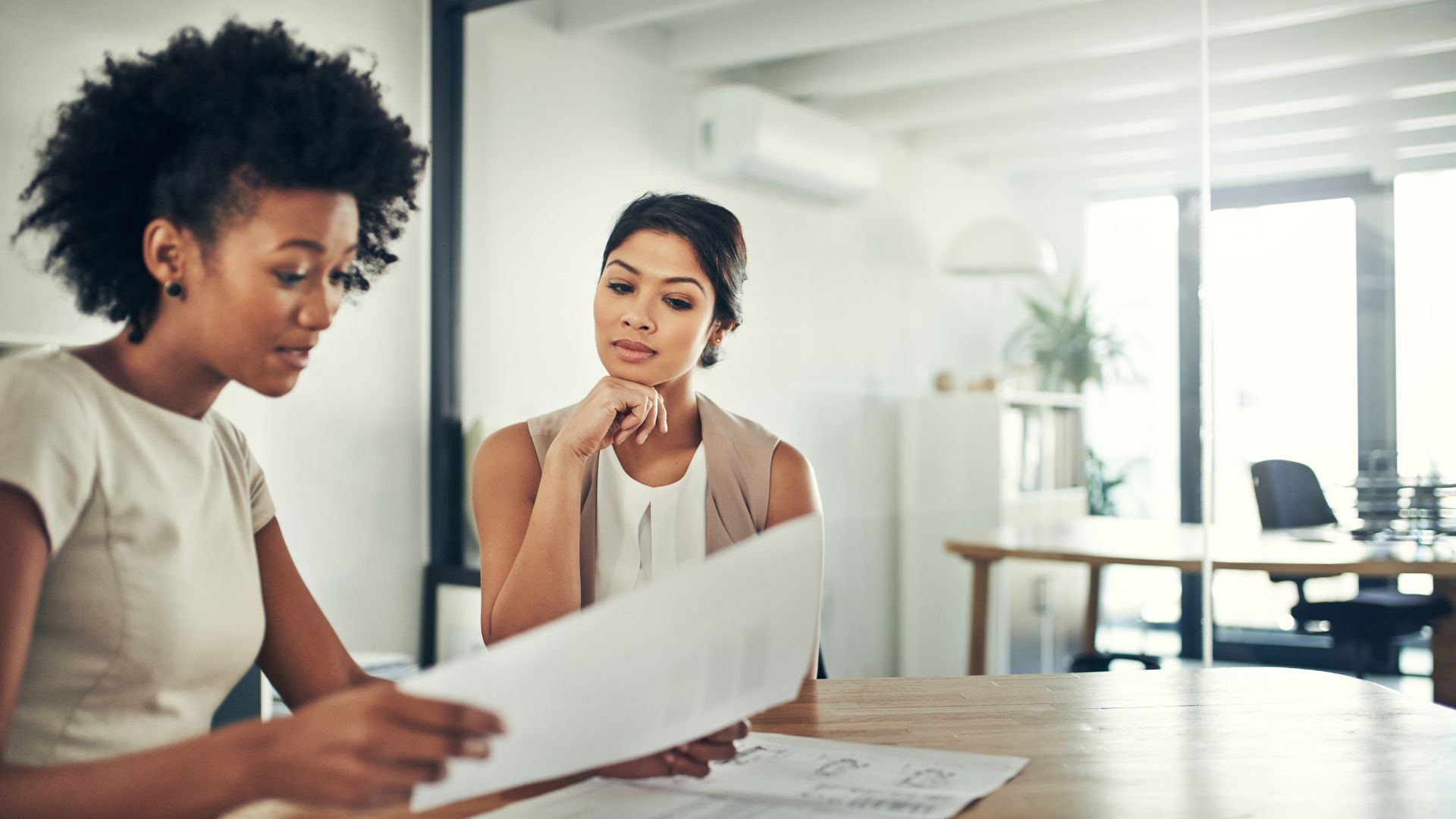 Two professionals carefully reviewing a well-formatted printed resume.