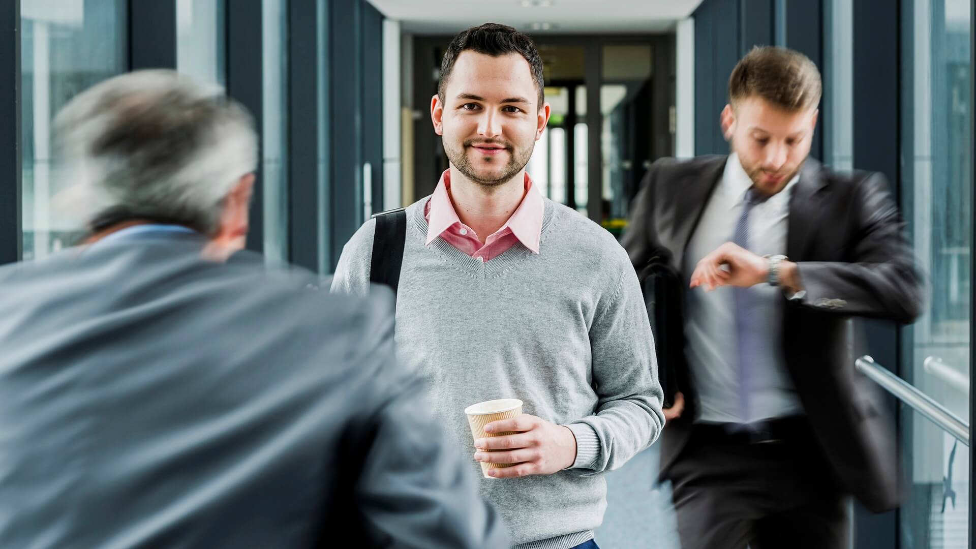 A man walking to his office holding a cup of coffee