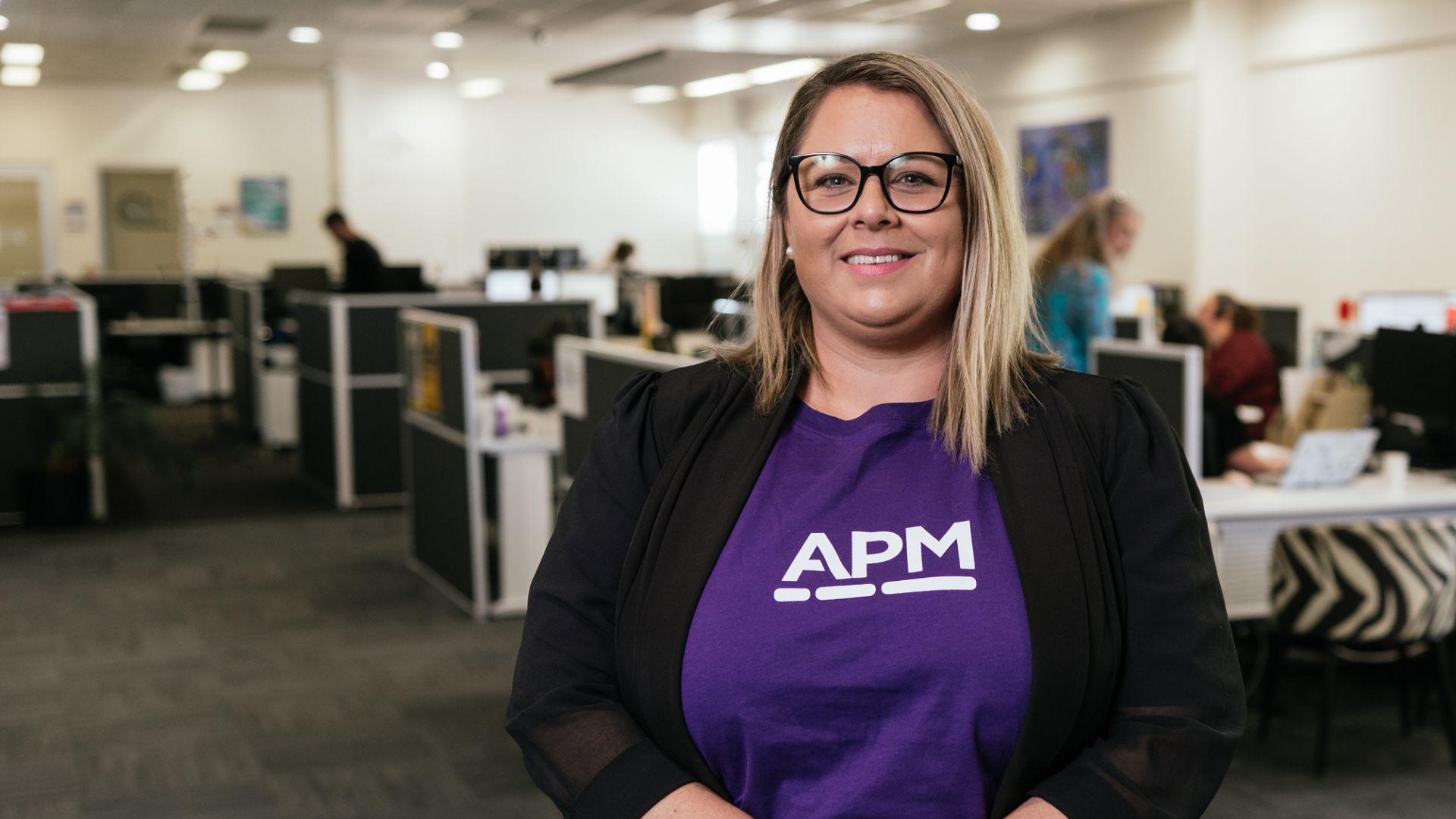 APM team member smiles in purple APM top