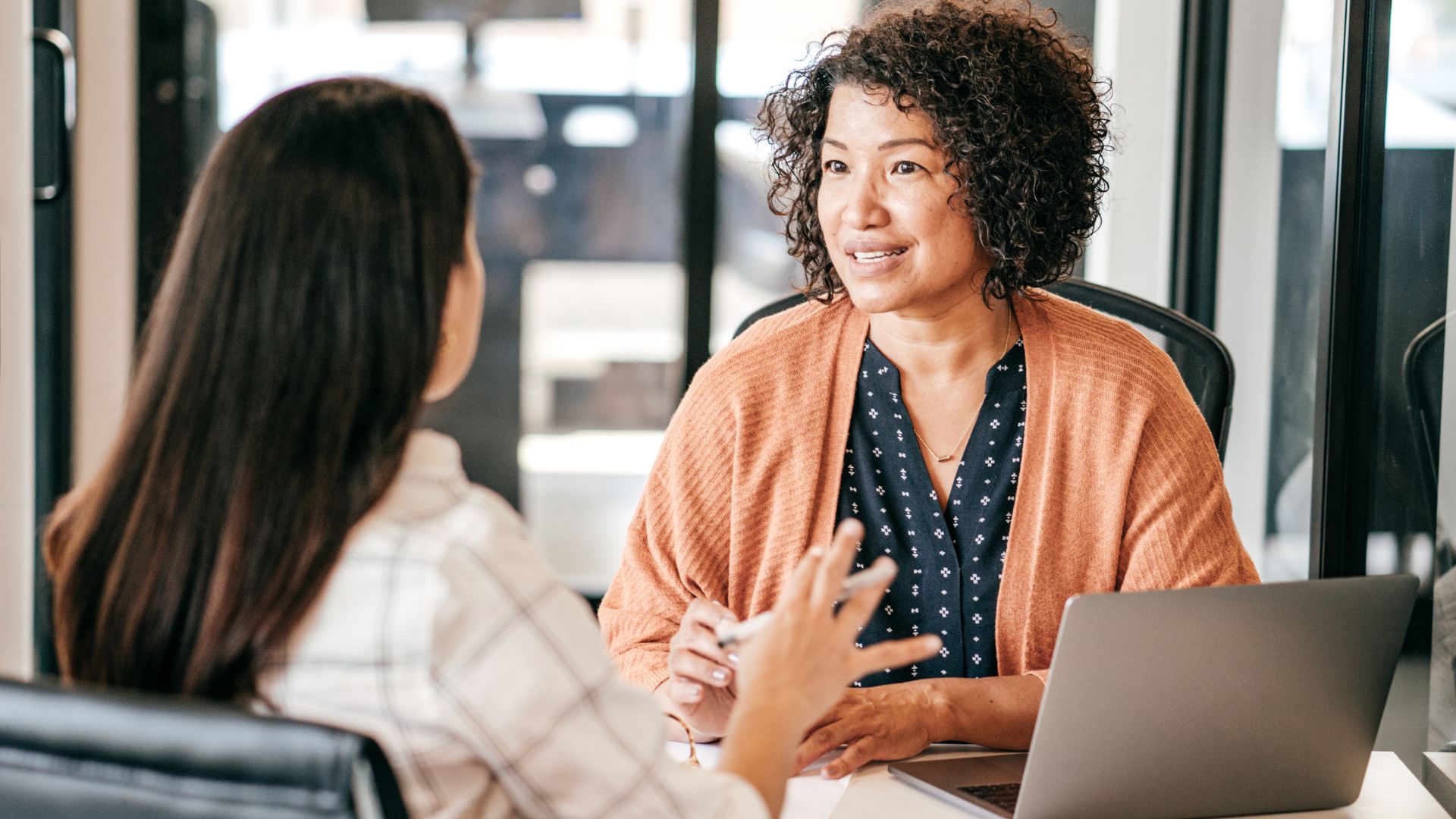 Woman smiles at an office desk with laptop