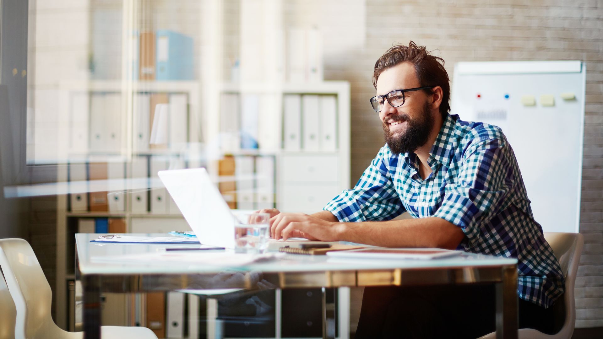 A man smiles working on his laptop