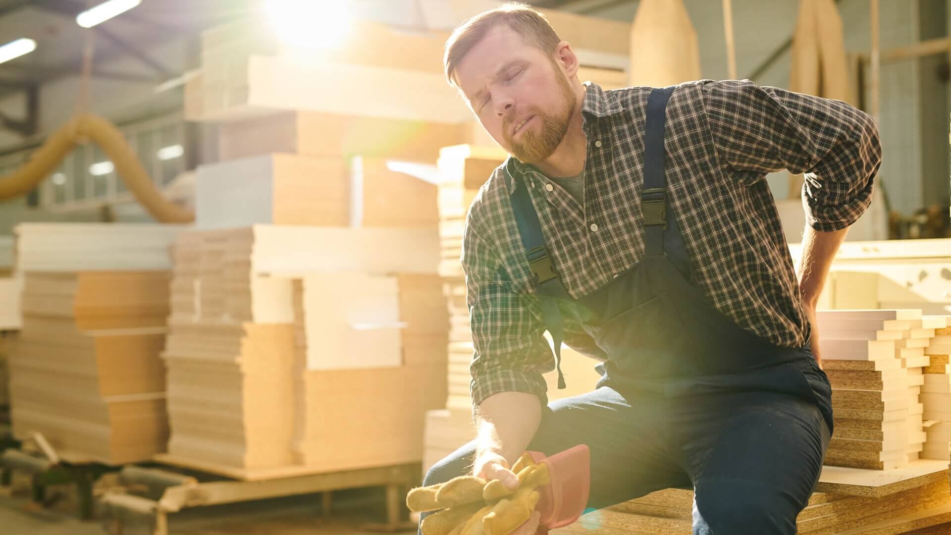 A man working in a warehouse sitting down and resting his sore back