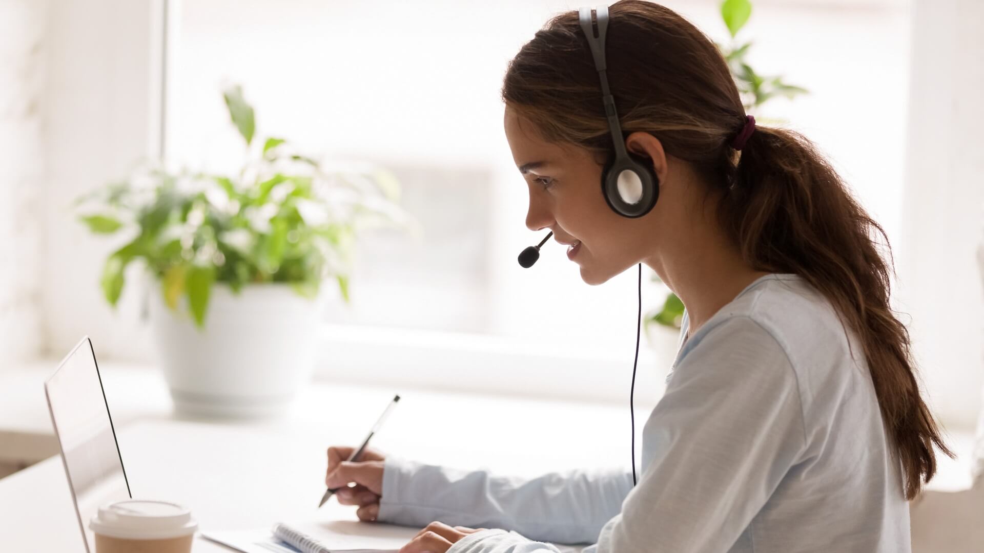 A woman working from her laptop wearing a headset