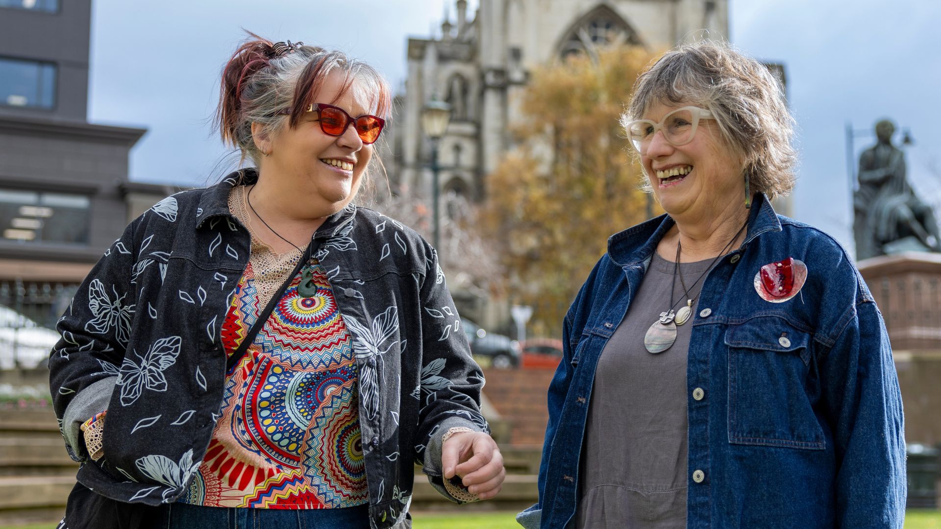 Two women walking and smiling outside a cathedral 