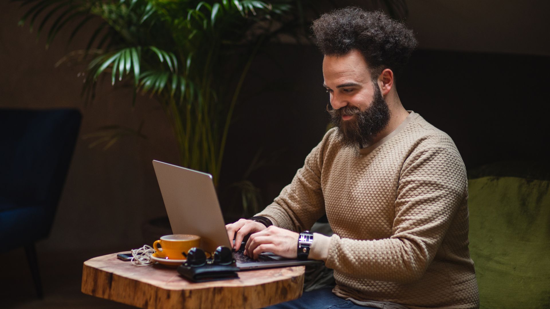 A man types on a laptop with a coffee