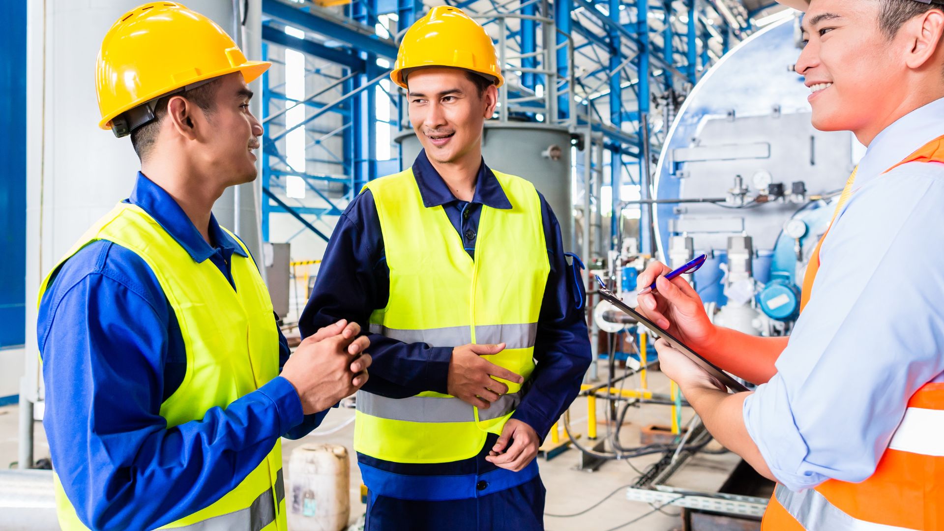 Three men smile in a warehouse