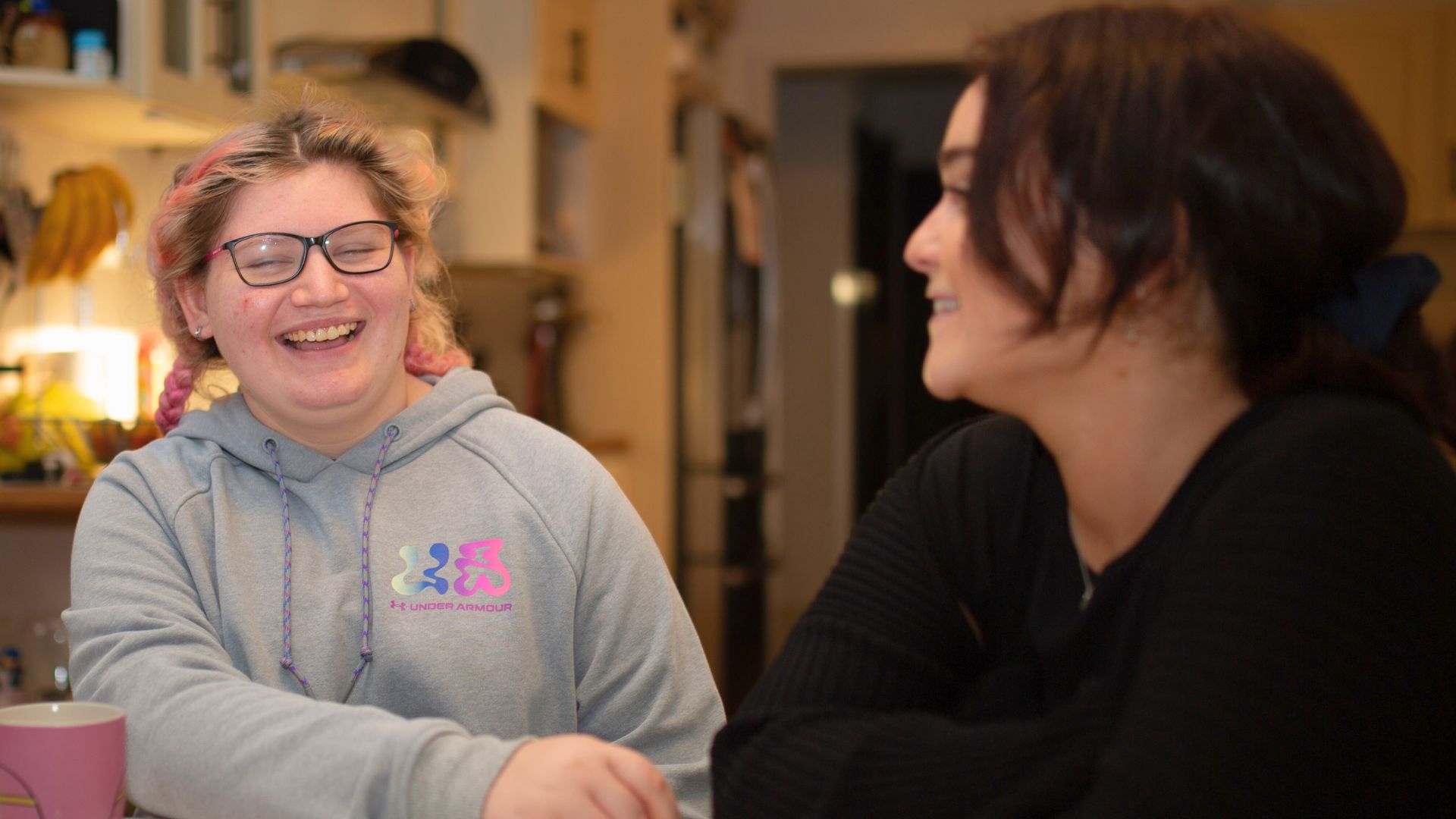 Amy sitting at a kitchen table chatting with Occupational Therapist Scarlette about her progress and goals, highlighting person-first therapy approach.