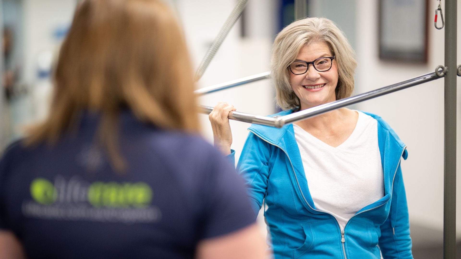 A client performs a pilates bar exercise while a Lifecare Croydon instructor offers coaching and technique support.