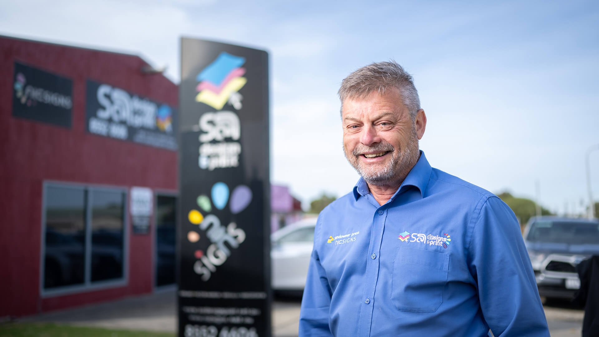 Employer Geoff smiles outside the business