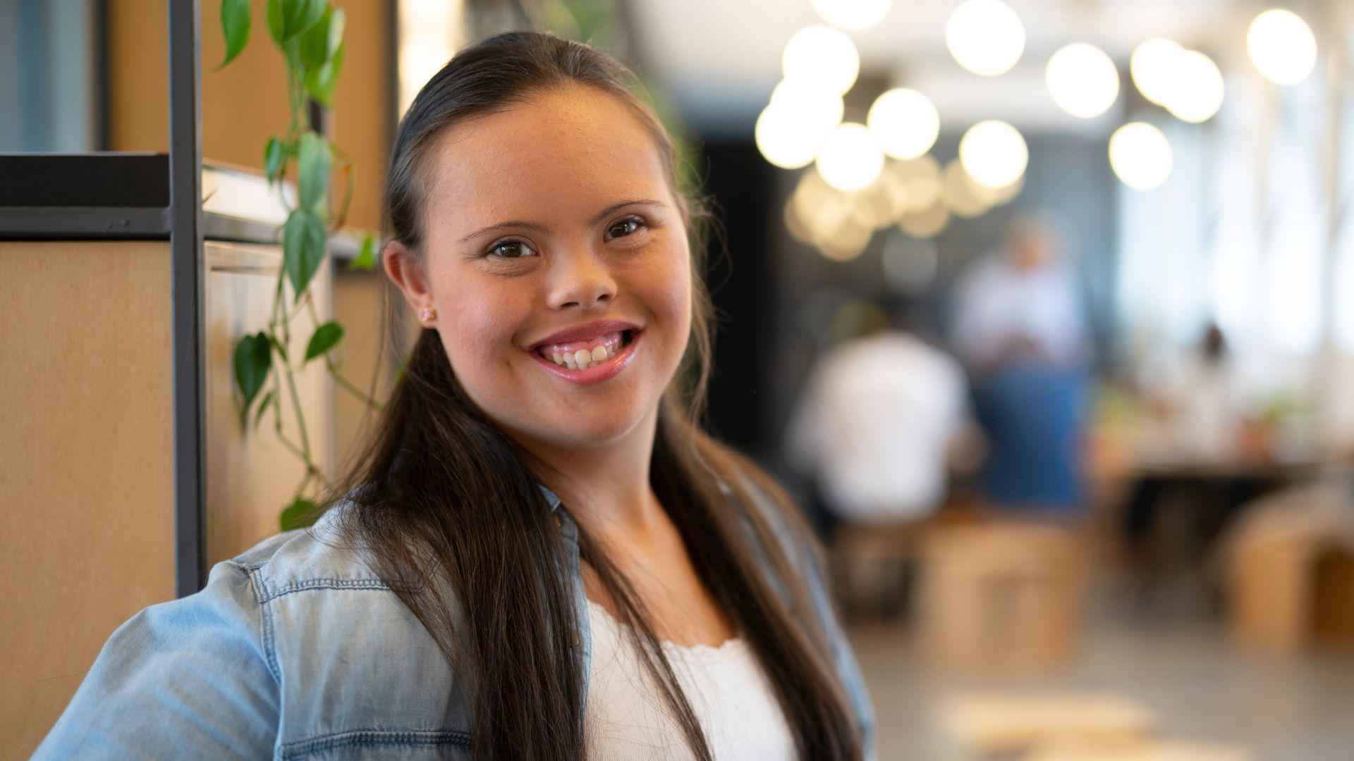 Woman with down syndrome smiles in a casual office workplace