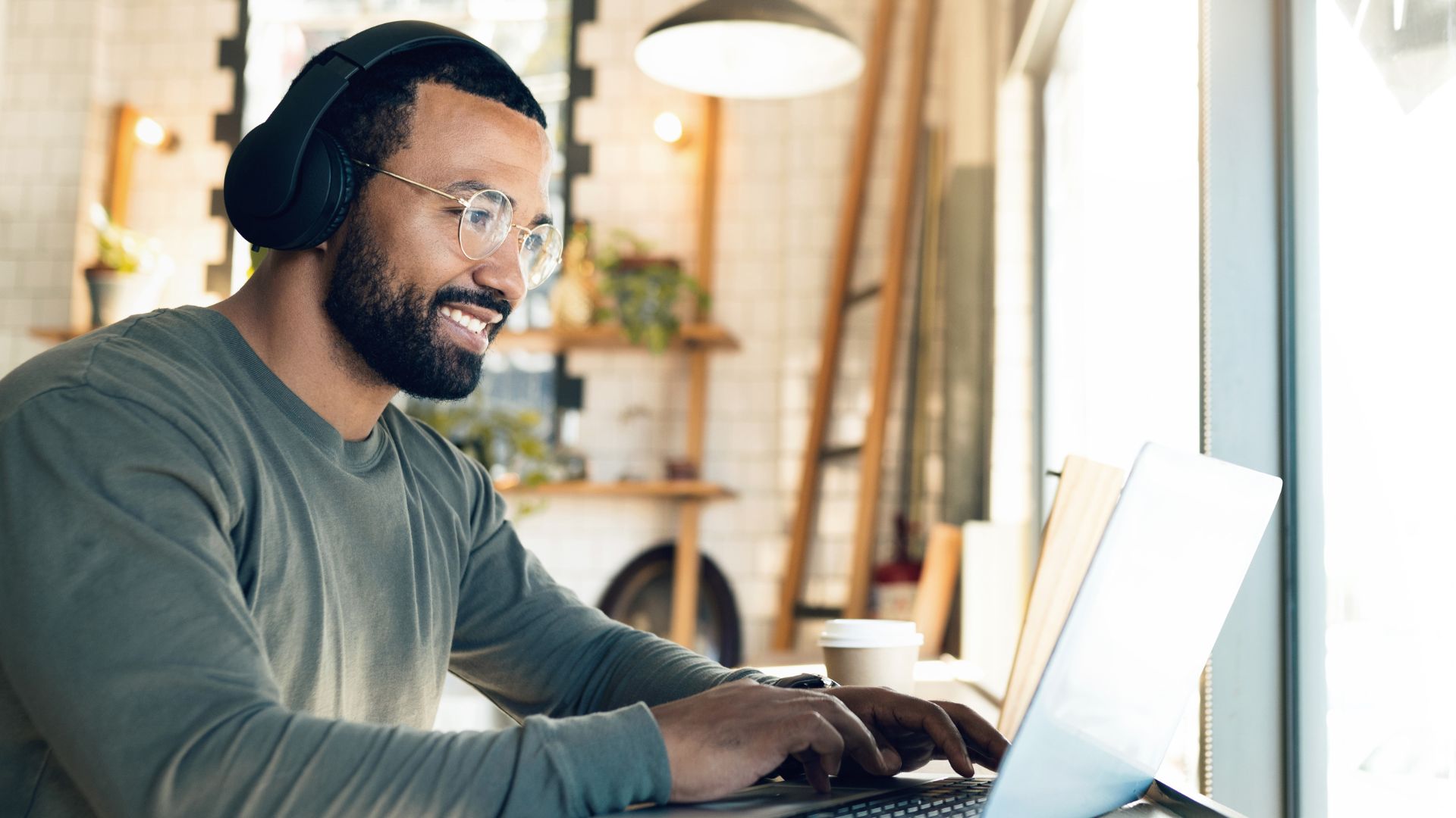 A man smiles as he works from a laptop as a copywriter