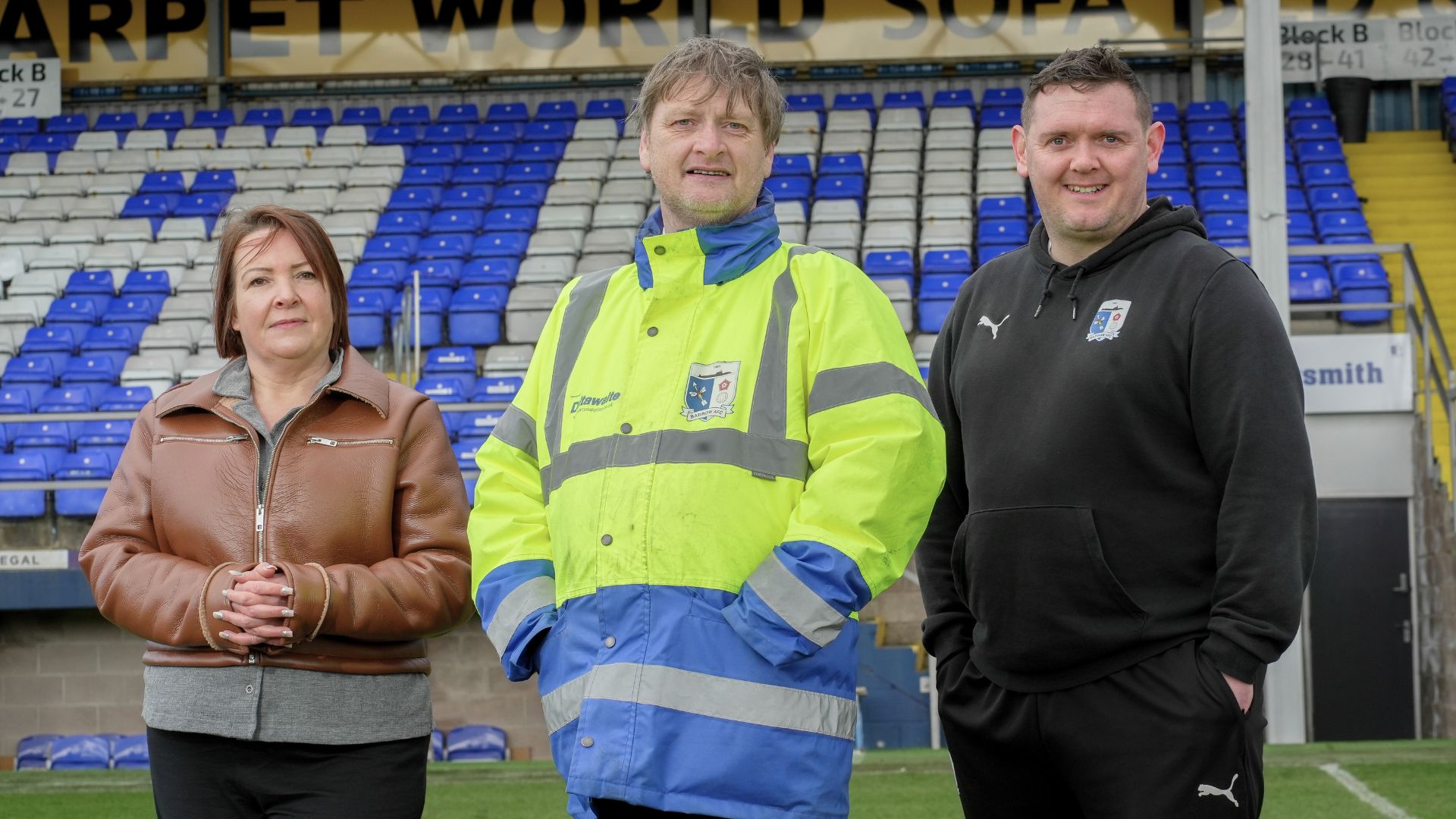 Mark, a match day steward supported by Ingeus through the Pioneer programme, standing with two colleagues inside Barrow AFC stadium, representing successful employment and teamwork.