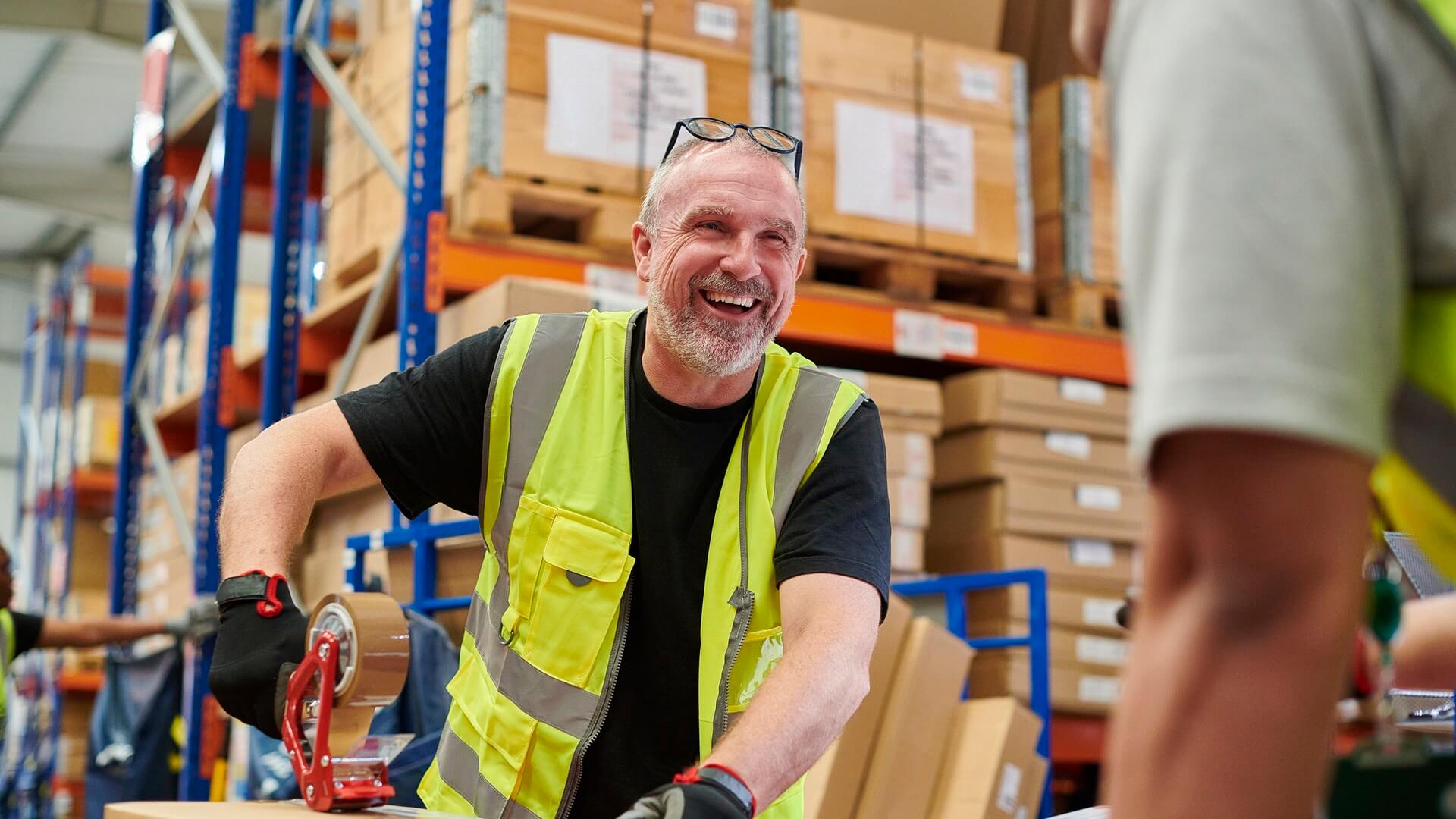 A man with Parkinson's and smiling while working in a warehouse