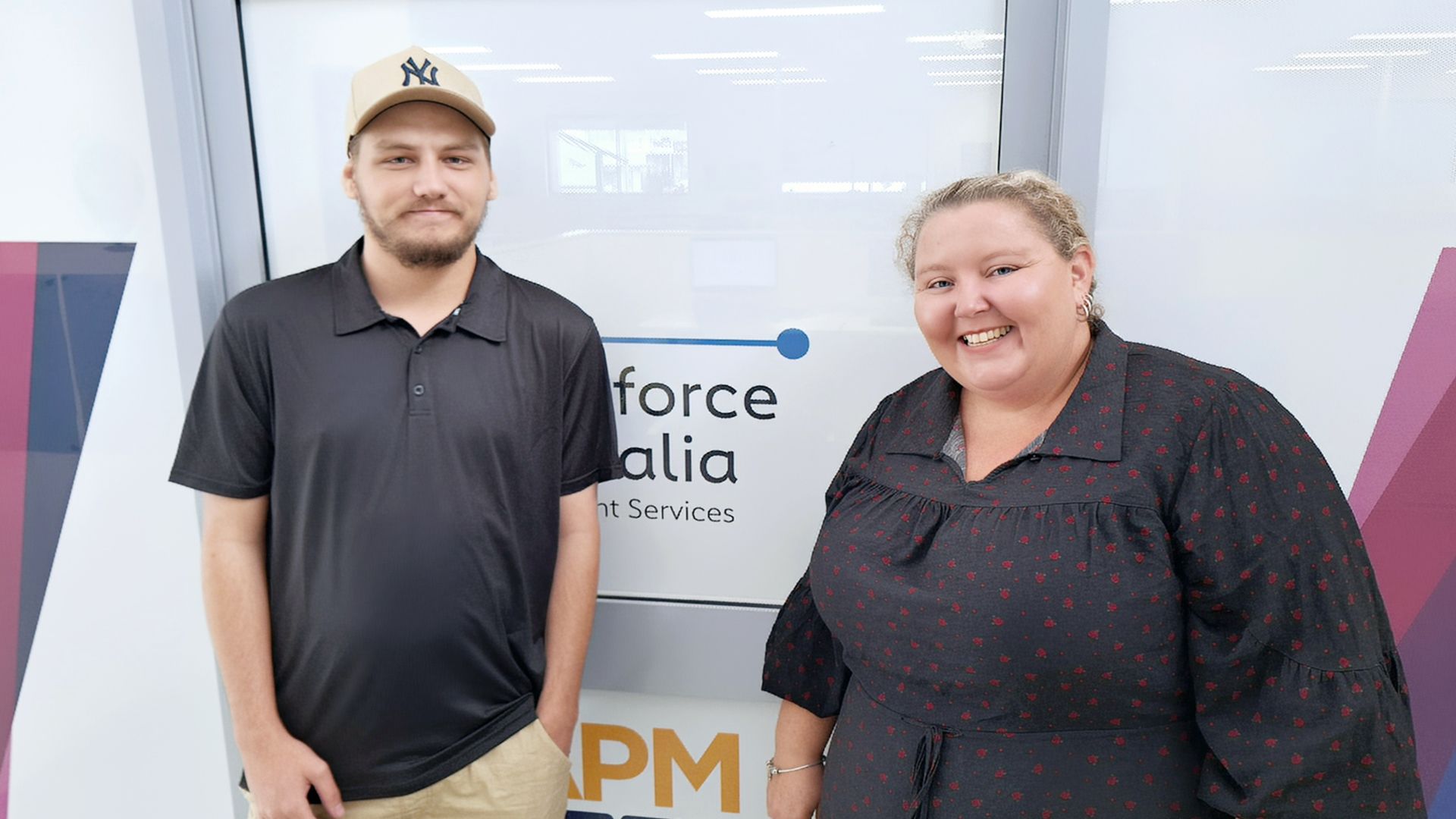 Cody, a Workforce Australia participant, standing with his consultant Jade in front of an APM Employment Services sign, highlighting support for job seekers.